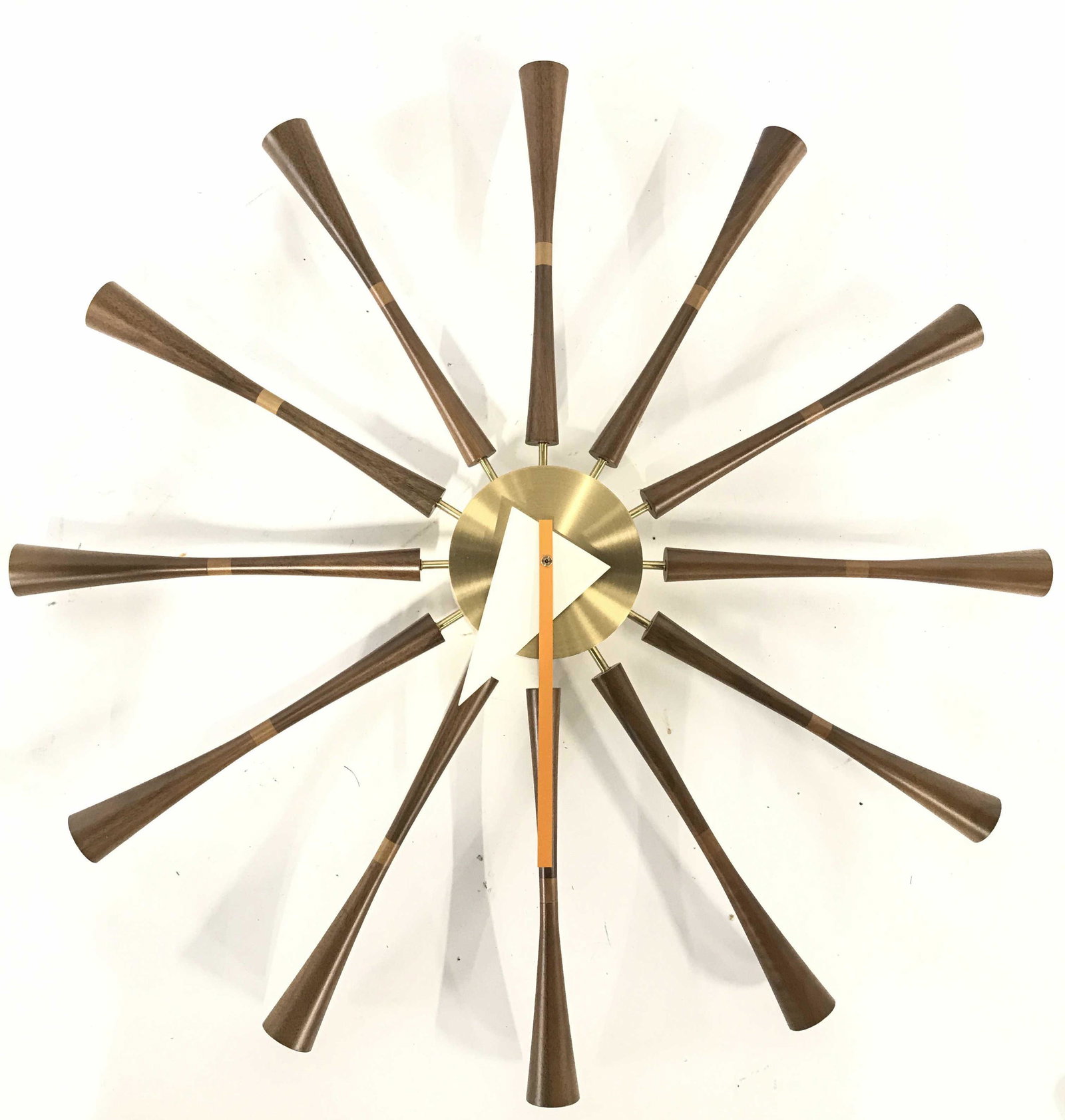 VITRA GEORGE NELSON Mid Century Modern Wall Clock: Tag on Backside of clock reads VITRA DESGINED BY GEORGE NELSON. Piece has gold toned center and wooden spindles. Piece measures approximately 23 inches wide and tall. Piece has 1 triangle shaped white