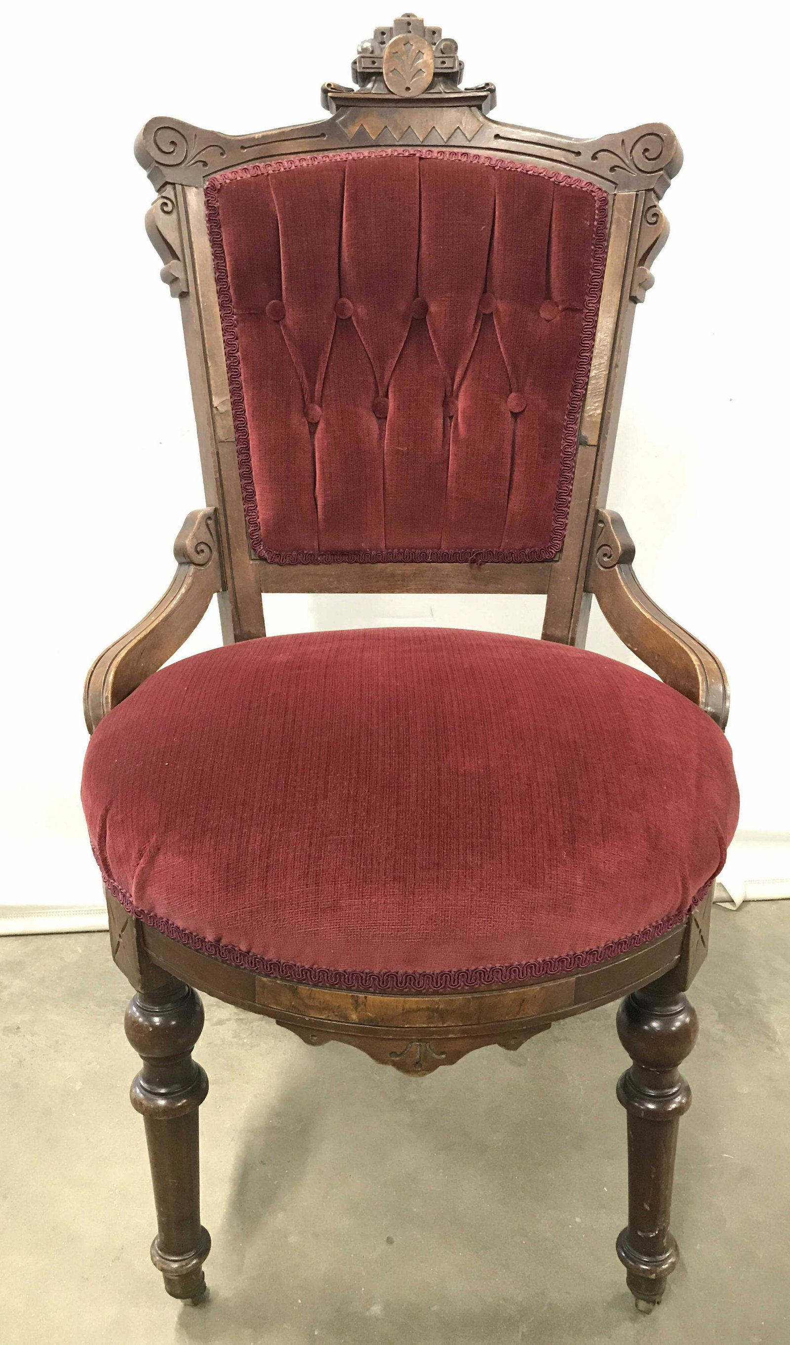 East Lake Antique Victorian Style Chair On Casters: Chair is vintage possibly antique. Piece has cranberry toned upholstery. Chair frame has intricately carved wooden Detail. Chair has 2 Casters on front legs. Backrest Of Chair is Tufted. Chair possibl