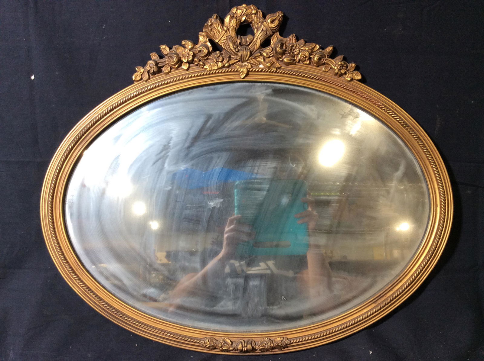 Antique Ornate Gold Leafed Oval Wall Mirror: Mirror has golD toned Ornately Detailed Frame. Mirror is oval shaped. Frame appears to be gold Leafed. Wall Mirror, Antique Mirror, Vintage Mirror, Ornate Mirror, Oval Mirror, ellipse Mirror. Piece me