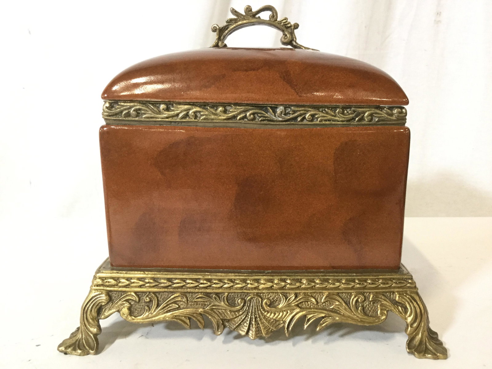Vintage Lidded Porcelain & Brass Keepsake Box: Keepsake Box has red toned trademark on underside, piece is porcelain with gold toned ornately Detailed Lid Handle, Base, feet and rim. Piece is vintage Possibly antique. Piece measures approx 9 inche
