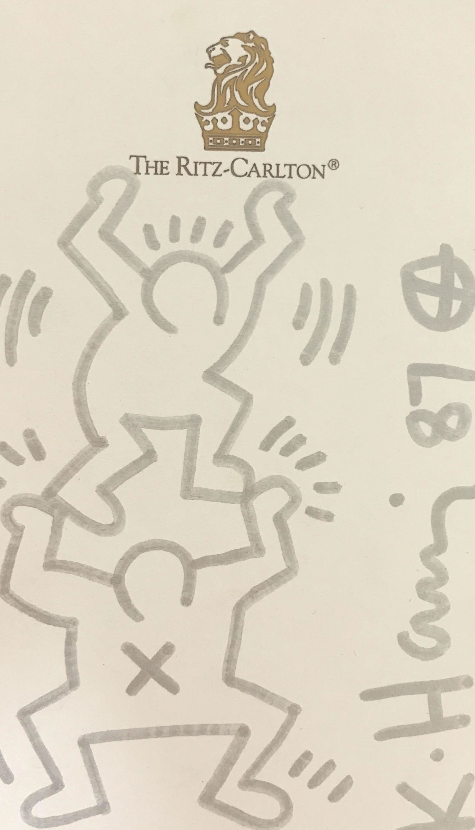 Signed Marker Drawing On Paper, After Keith Haring: Appears to be a silver marker drawing on The Ritz Carlton note paper, two figures, one smaller figures balancing on larger figure’s outstretched hands, signed K. Haring 87vertically on lower right s