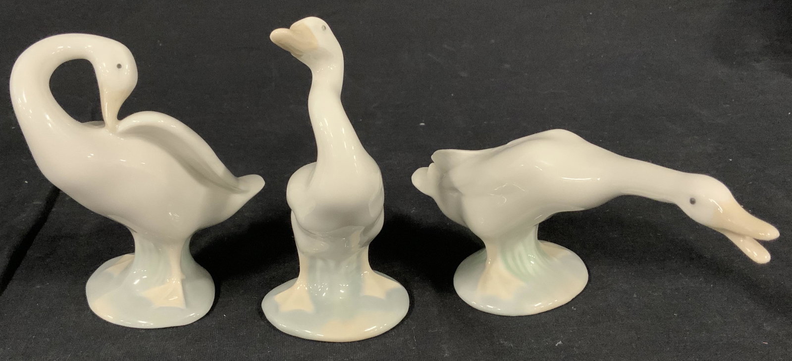 Set 3 LLARDO Porcelain Duck Figurals: This is a trio of porcelain swans. Each piece depicts a swan in a different pose. The statues come from LLADRO, and are made in Spain. The underside reads LLADRO, HANDMADE IN SPAIN, DAISA. The largest