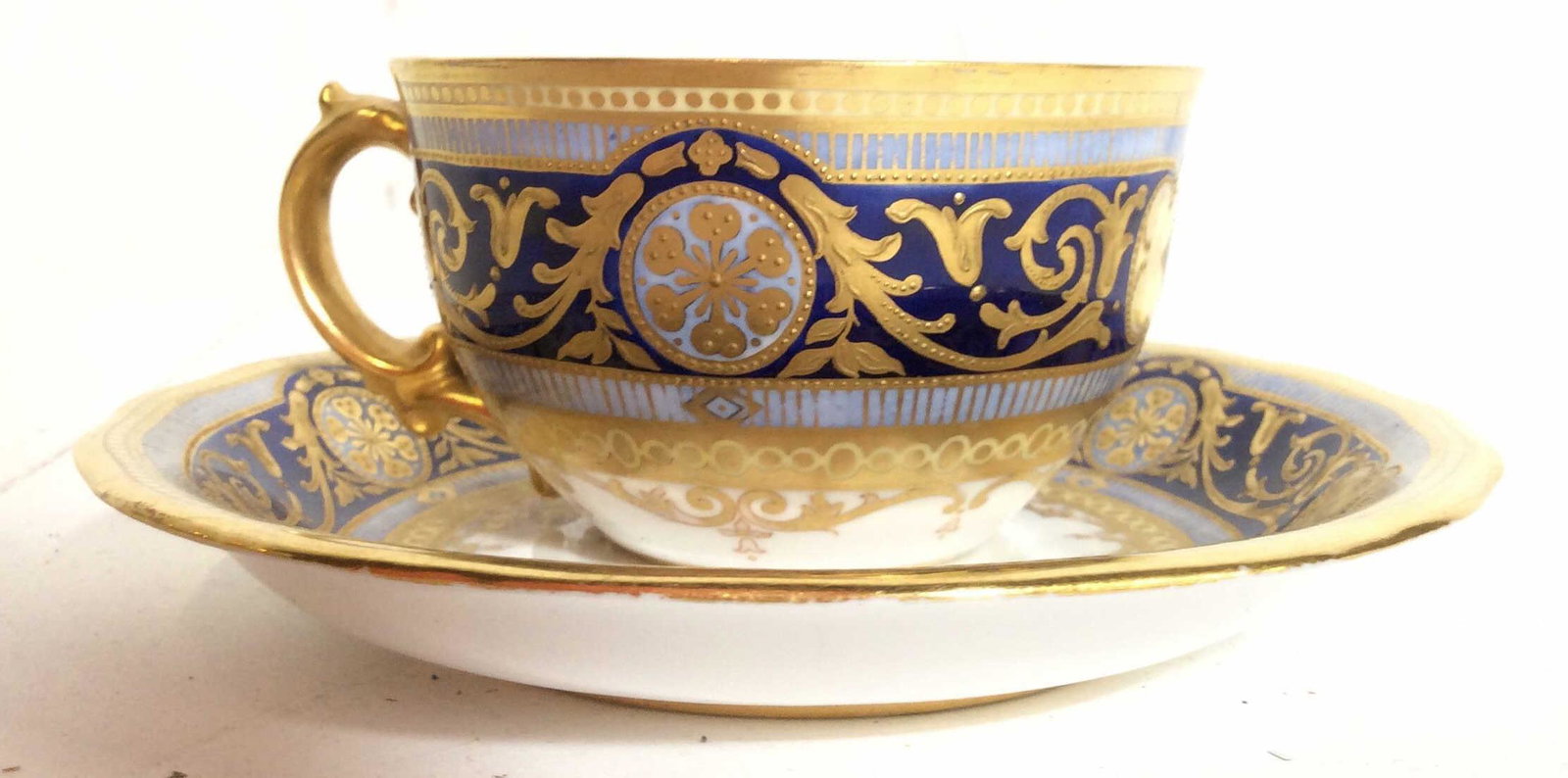 Royal Crown Derby Cup and Saucer, England: Blue and gilt design marked on underside for Royal Crown Derby Made in England, some minor wear to paint, saucer measures approx 5 in in diameter. tea cup, tea service for one, tableware, tabltop acce