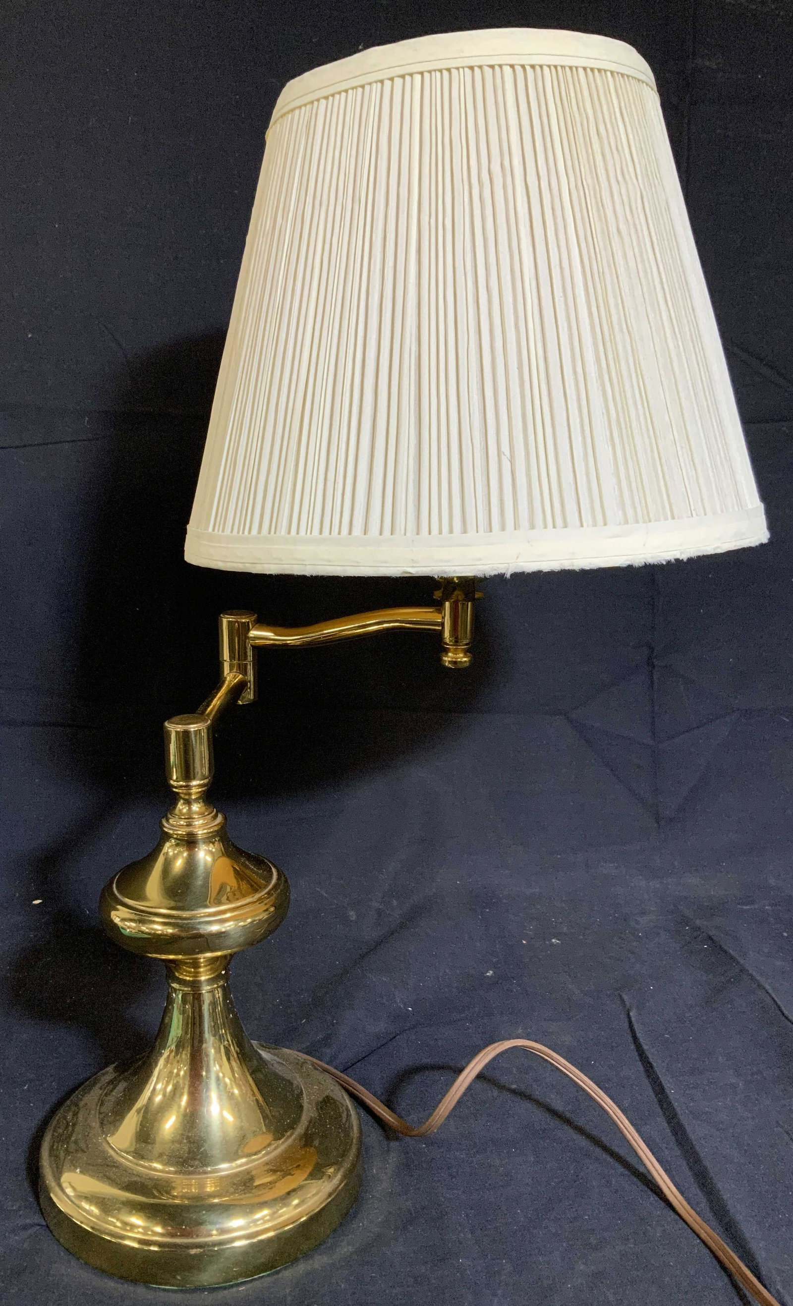 Gold Toned Brass Swinging Arm Lamp: Lamp is gold toned and brass. Lamp includes shade and finial. Lamp has swinging adjustable arm. Brass lamp, adjustable lamp, table lamp, side table lamp. home furnishings and accessories Piece measure
