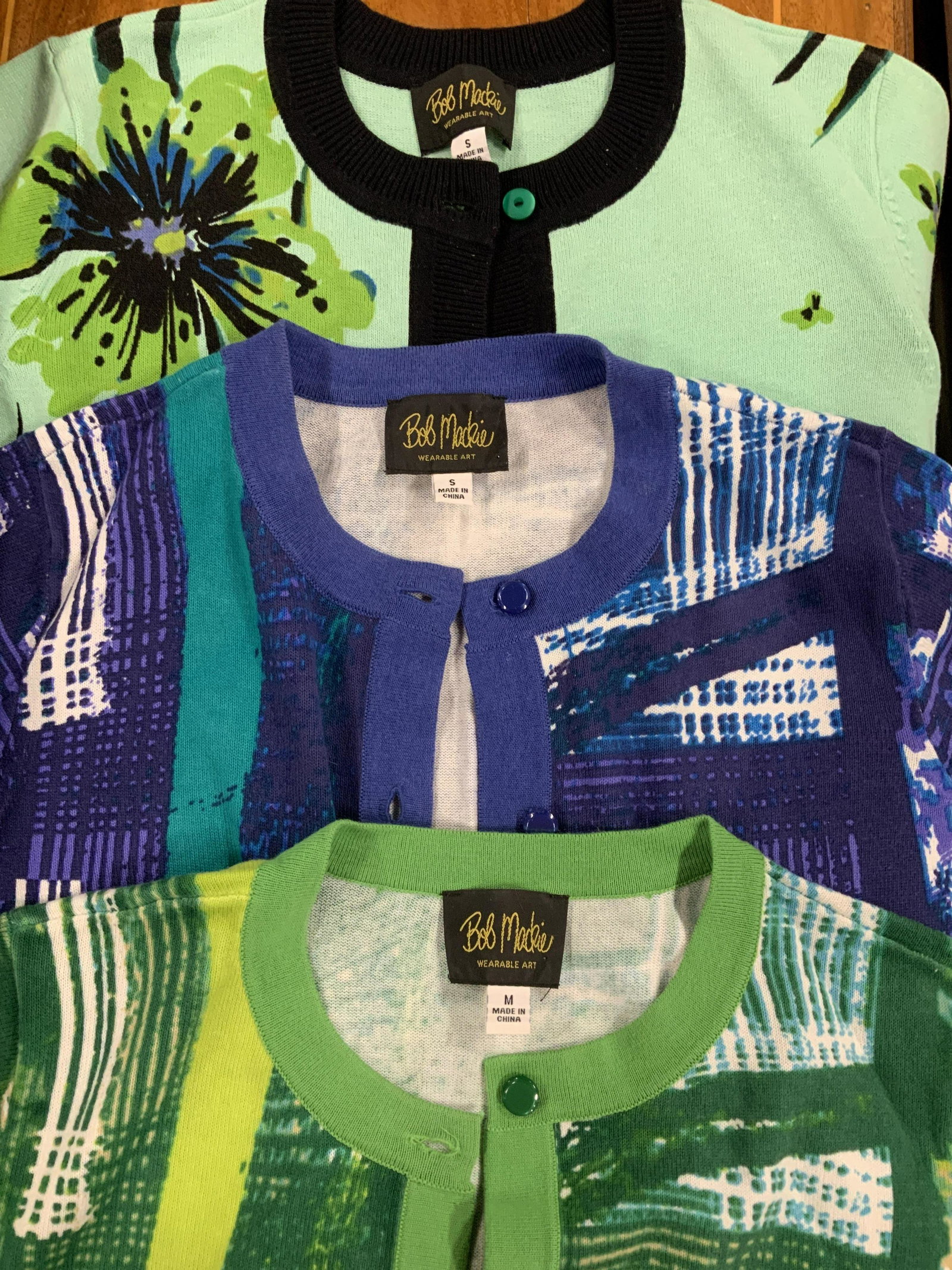Lot 3 Bob Mackie Wearable Art Button Sweaters: From his high-end ready-to-wear line. Small and Med. vibrant mint green, grasshopper green (med) and violet/blue. Plaid print design or floral design. All 60% Cotton, 40% acrylic. 2 of the sweaters ha