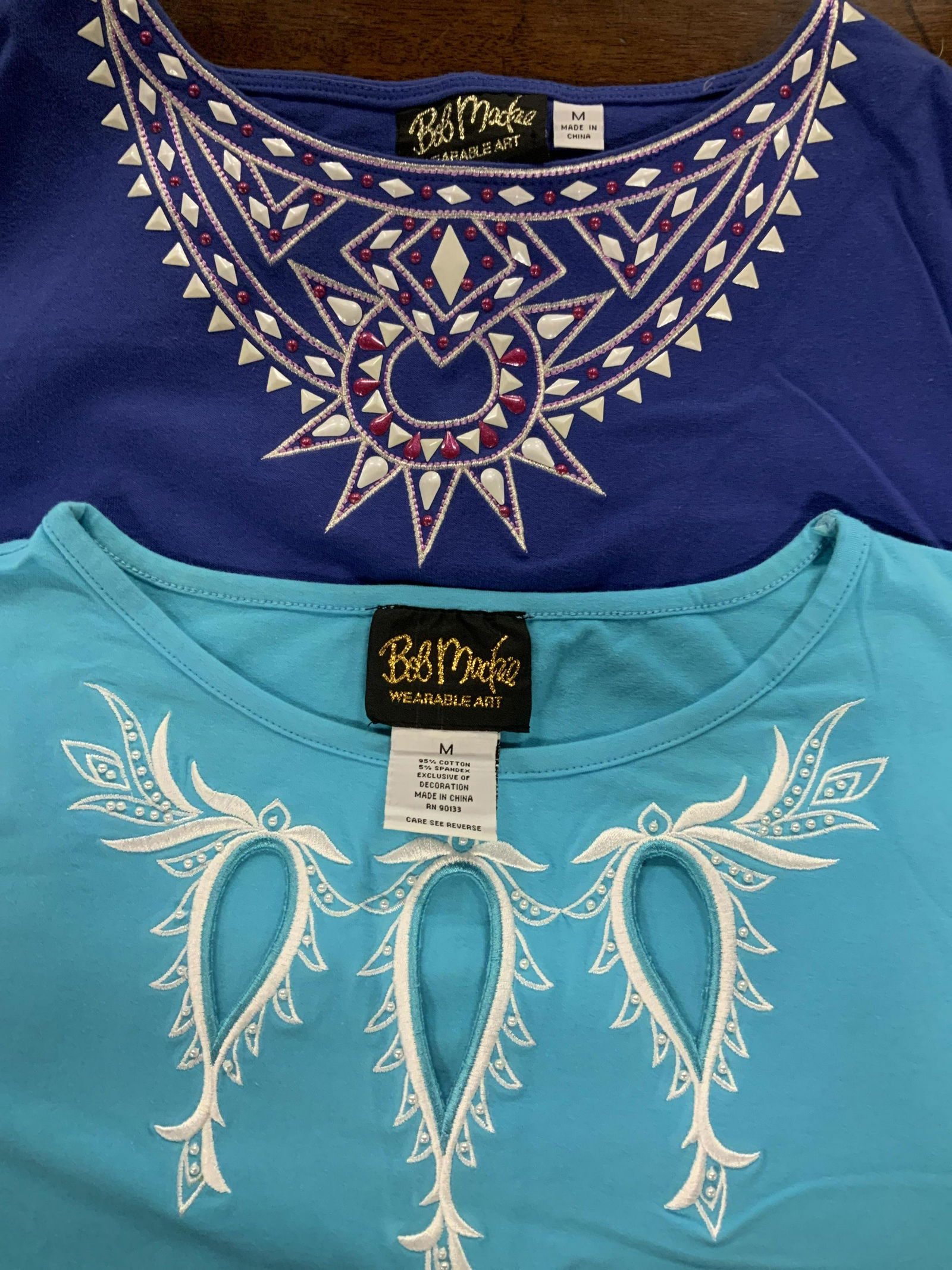 Lot 2 Wearable Art by Bob Mackie Cotton Tee Shirts: Both 95% Cotton wide crew neck designer tees from bob mackie’s high end ready to wear collection. 3/4 in sleeves. Sky blue with white embroidery & royal blue with southwest style collar design. ligh
