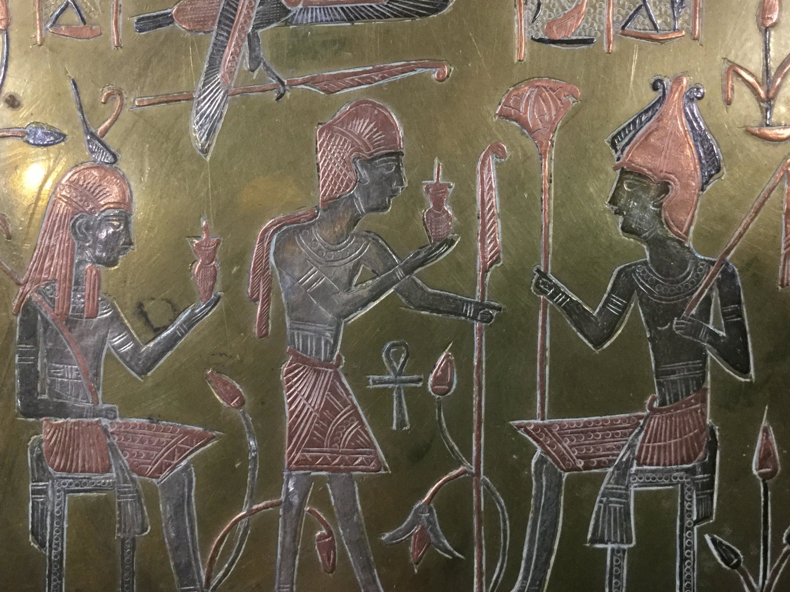 Egyptian Style Etched Brass Tray: This is a brass tray that has been carved to depict figures in an ancient Egyptian Style. The art is colored in copper and silver tones. The piece measures approx 13.25 inches in diameter. There is we