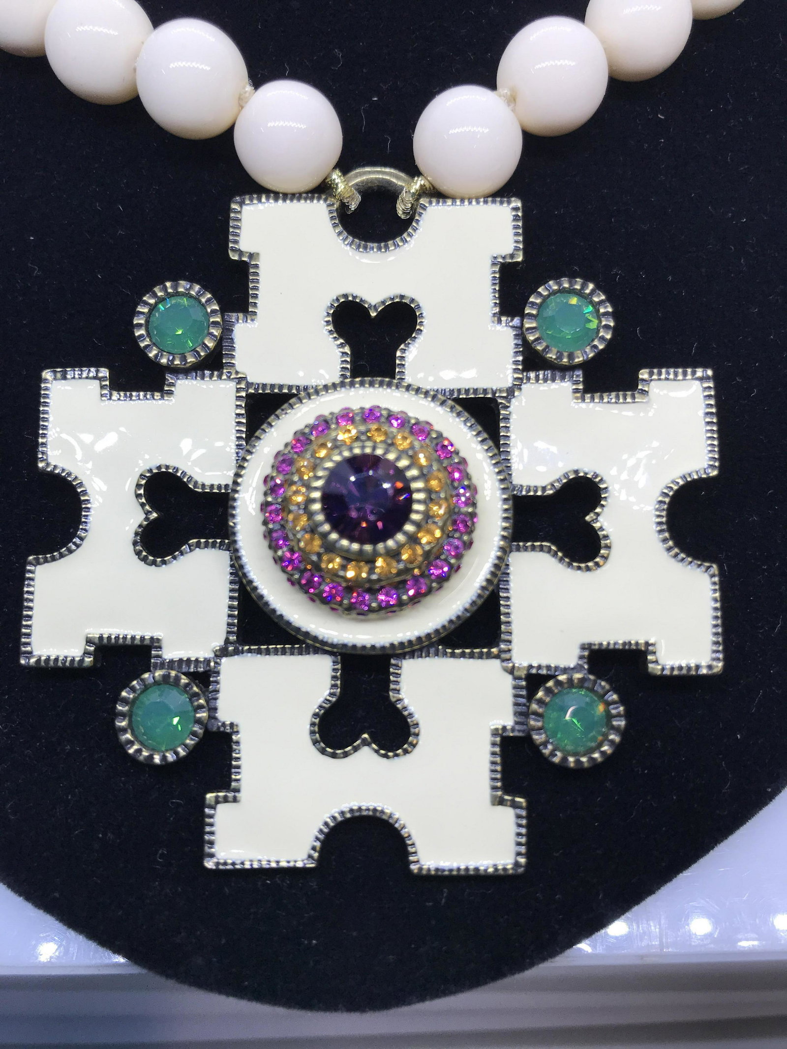 Heidi Davis Designer Enamel Crystal Pendant Neck.: Adjustable necklace, cream colored round beads, app 10 mm with oversized Crystal & Enamel Pendant. Center Crystal Design flanked on all 4 sides with the initial ‘M’. Brass toned metal rims, 14 - 1