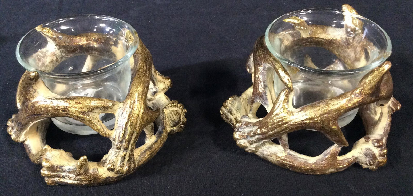 Gilded Horns Tea Light Holders: Set of 4 Mixed Media tea light holders. Detailed to look like deer horns wrap around the round glass holders for candles. Horns are detailed with gold tone paint and carved to resemble horns, tablewar