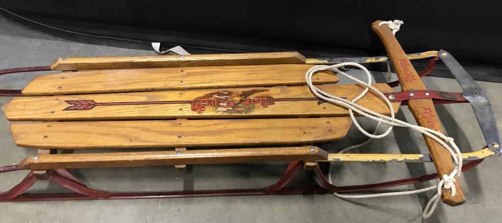 Vintage FLEXIBLE FLYER Wooden Sled: This is a vintage, possibly antique, wooden sled with metal runners. The piece is from FLEXIBLE FLYER. The piece includes a rope that allows for steering. The piece measures approx 46 inches long, and