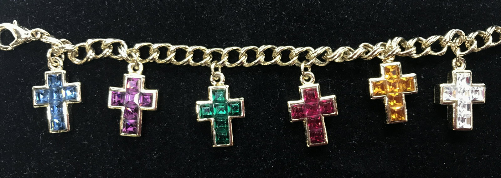 Signed Carolee Rhinestone Cross Charm Bracelet: Luxury jewelry designer Carolee, signed on attached charm. Curd gold tone link chain. 7 dangle cross charms, measure almost an inch long, gold tone polished metal. Can be adjustable length, lobster cl