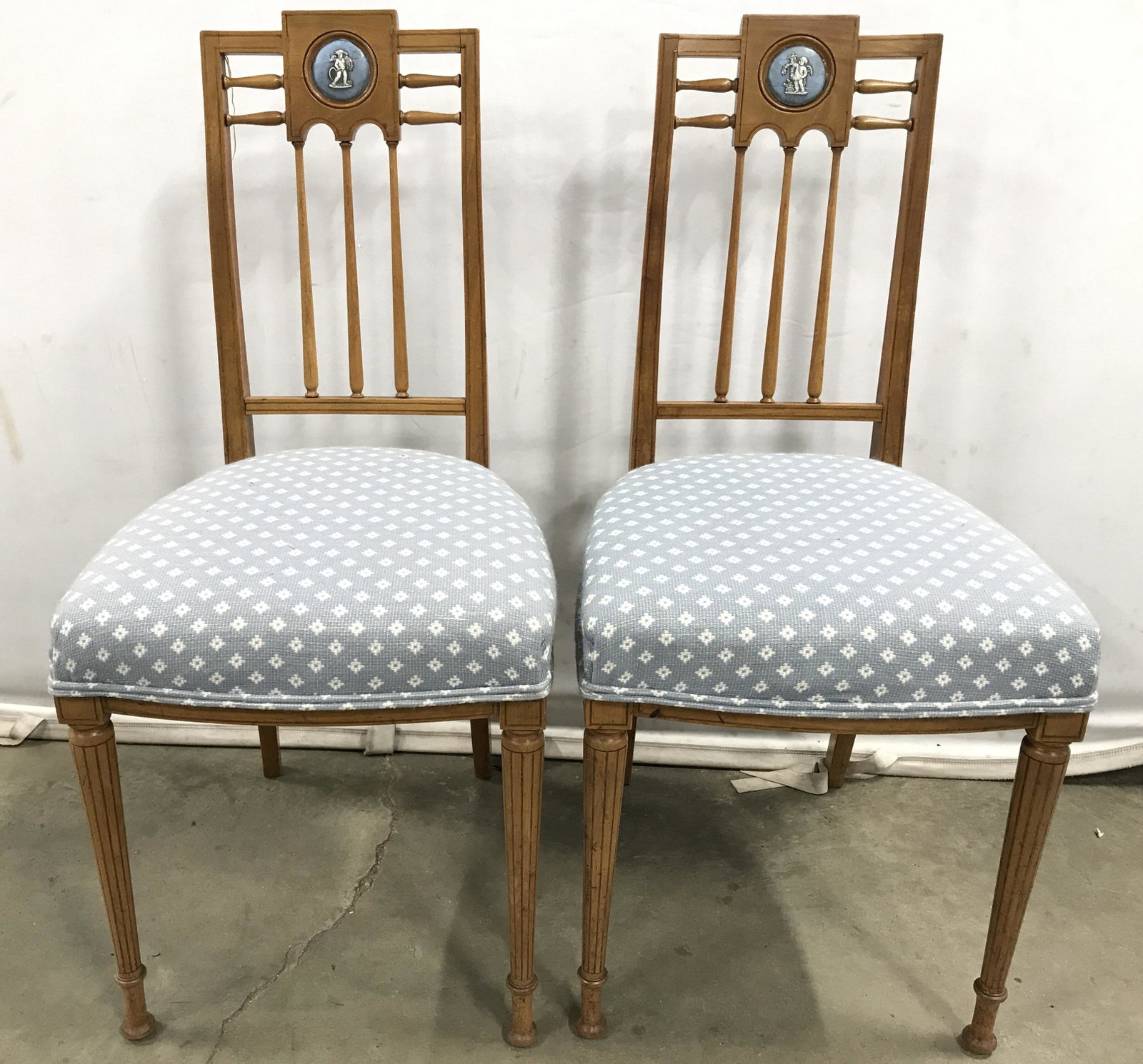 Antique Wooden Side Chairs W Ceramic Cherub Inlay: Lot includes 2 chairs each are antique. Both have Ceramic Cherub Inlay at top which resembles Wedgwood. Seats have double welted Upholstered edges with tones of white & powder blue. Backrests have car