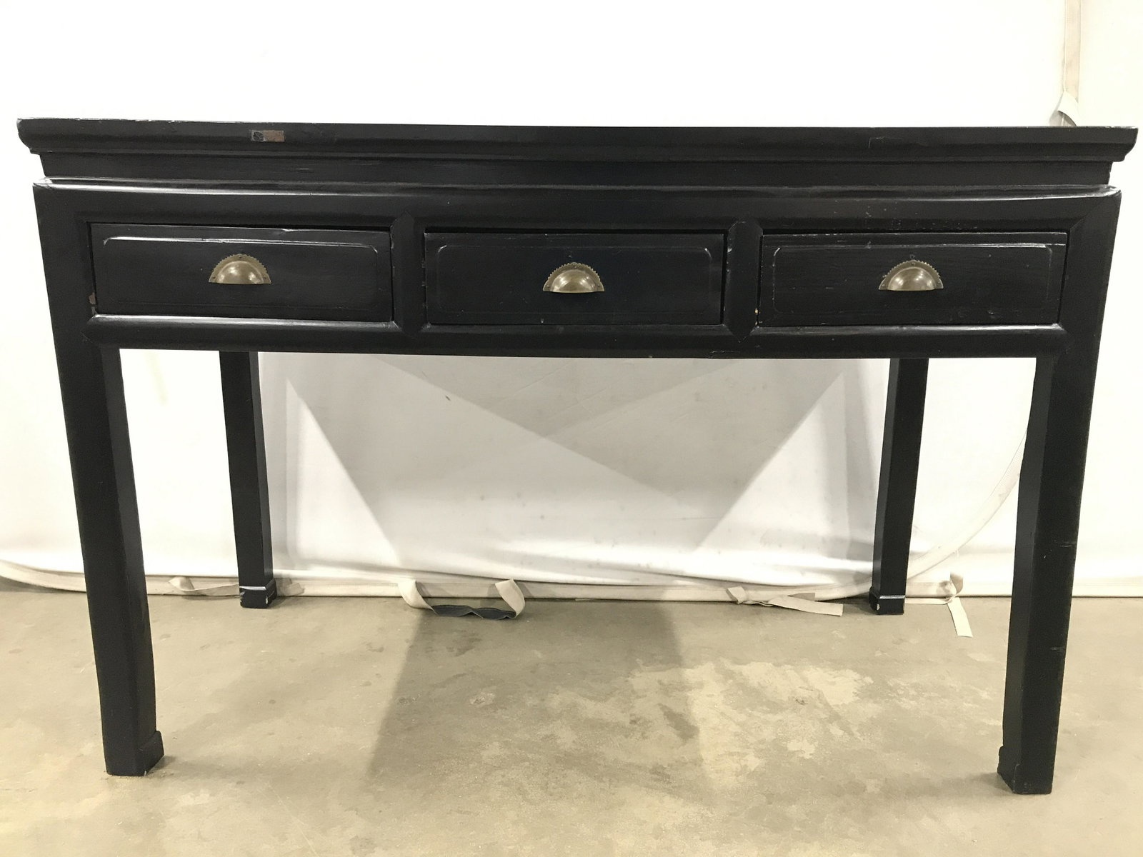 Antique Asian Carved Wooden Console Table: Console Table is black toned & wooden. Piece has 3 drawers each with gold toned handles. Table is possibly hand carved. Piece measures approximately 50 inches long 34 inches tall 23 inches deep Asian 