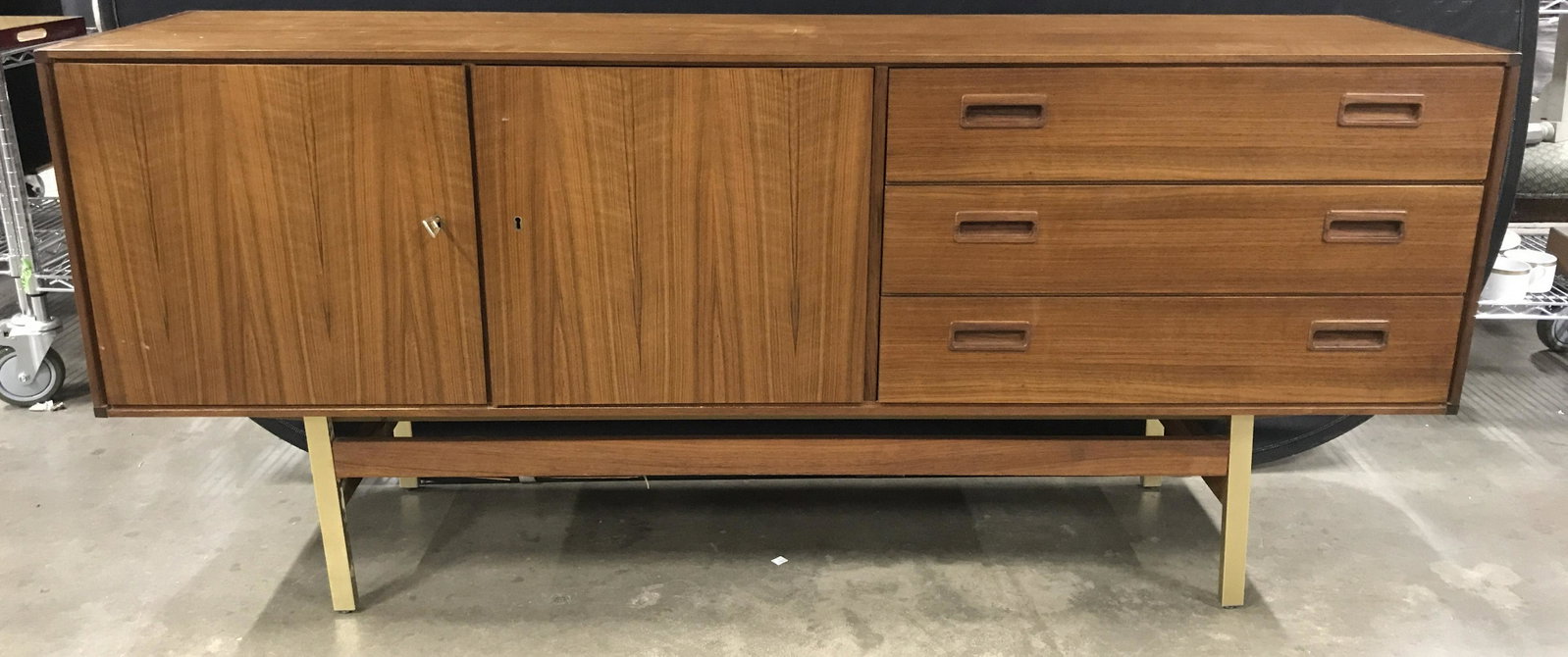Mid Century Modern Danish Style Credenza: Mid Century Modern Wooden possibly teakwood Credenza with gold toned metal and wooden base, three stacked side drawers on right and two door cabinet on left, marked with label on interior that reads P