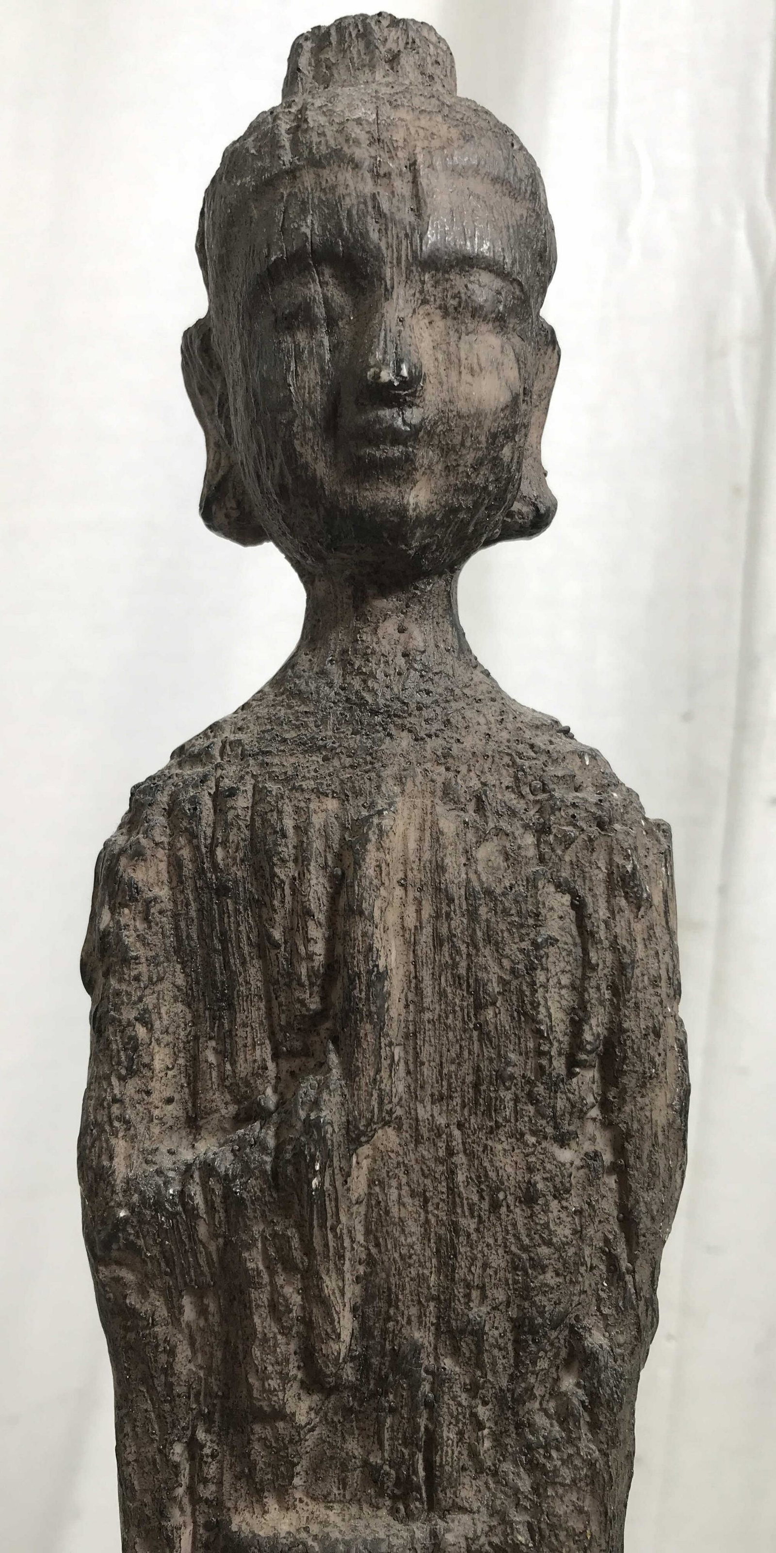 Wood Style Guanyin Deity Statue: Composite material formed and painted to resemble roughly hewn dark toned wood, figure with head dress and lifted hand, chips and wear to material. Measures approx 23 in by 4 in by 4 in, guanyin, deit