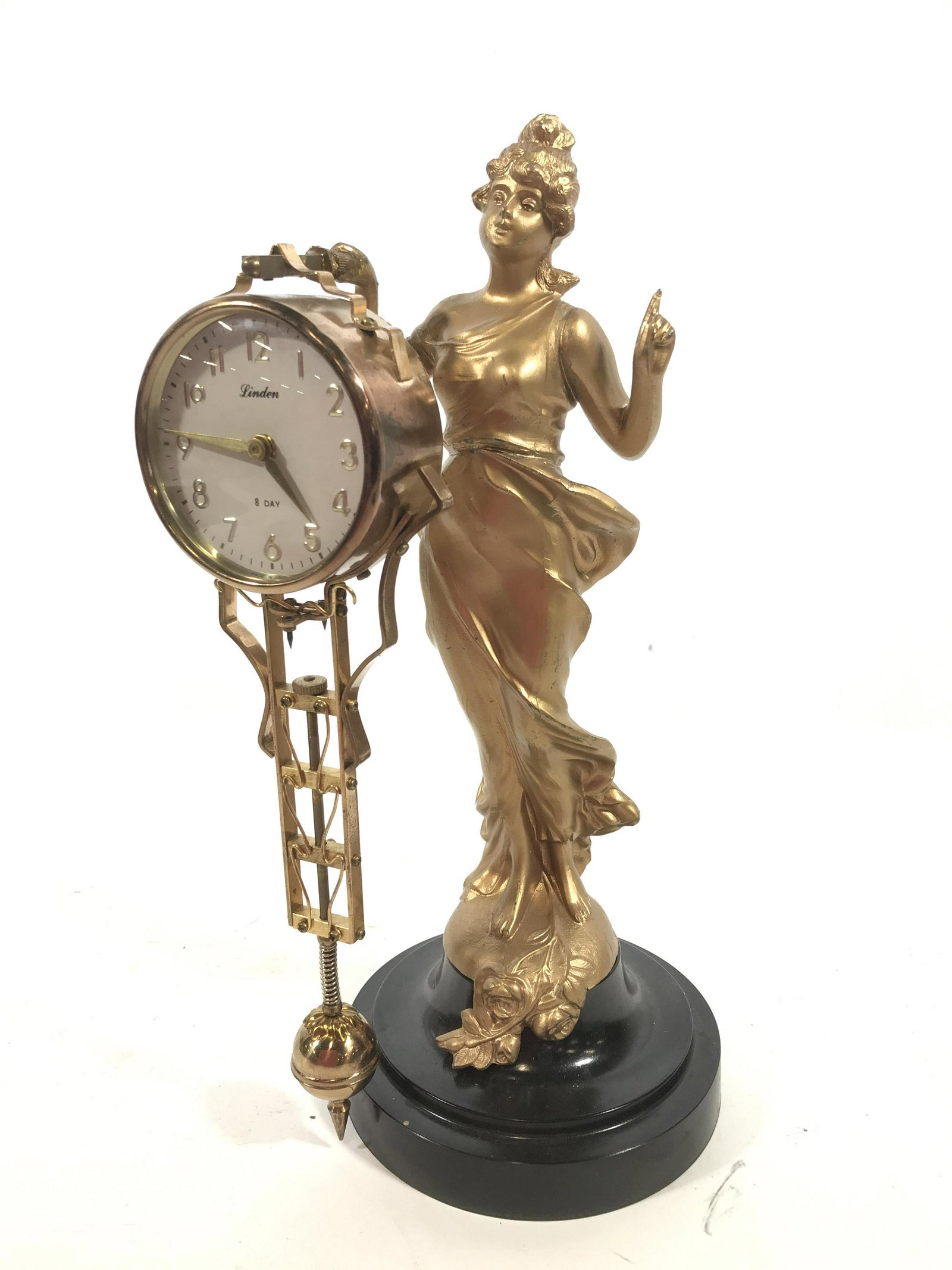 Art Nouveau Figural Linden Desk Clock: Clock face reads Linden 8 Day, made in Japan, clock with large pendulum style attachment gold toned finish, Figural appears to be metal with gold toned finish, Woman with flowing dress and floral desi