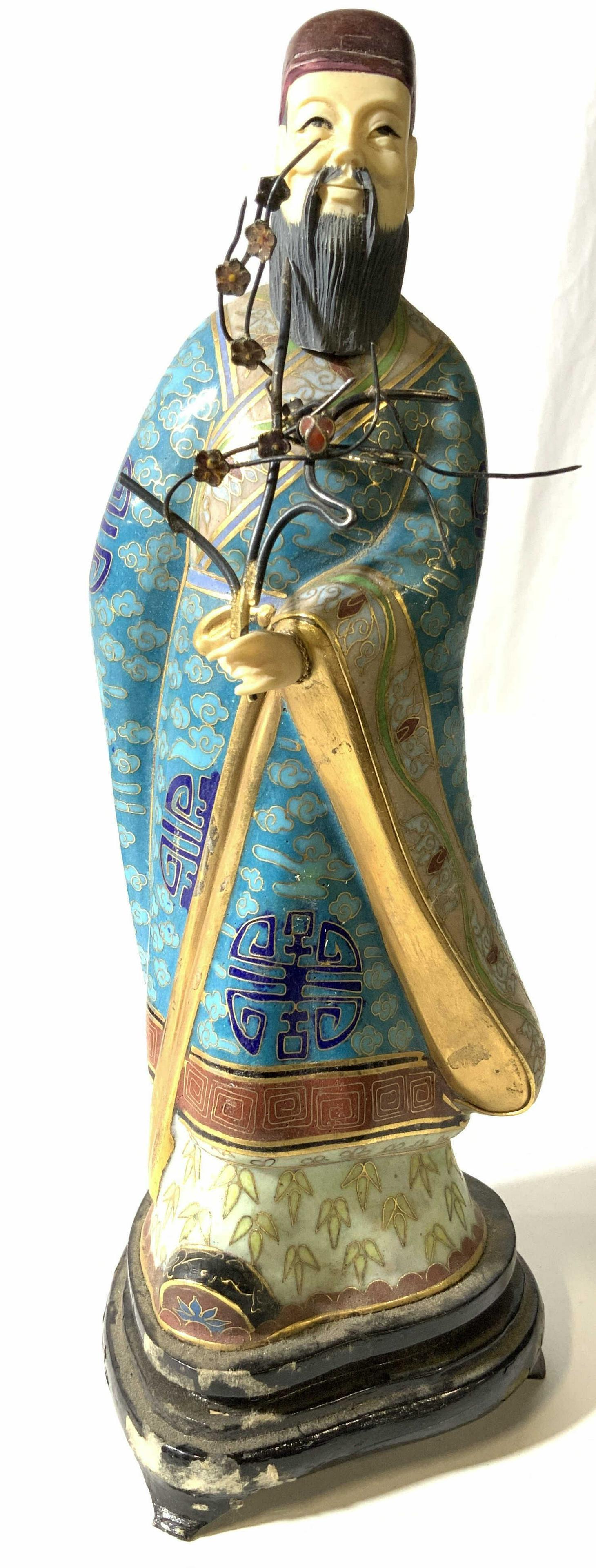 Asian Enamel Cloisonné Figural: Man with beard dressed in robes with cloud and plant inspired designs, brass toned metal wire cloisonné, bright enamel in tones of greens, blues and reds. Carved material hand and face, appears to be
