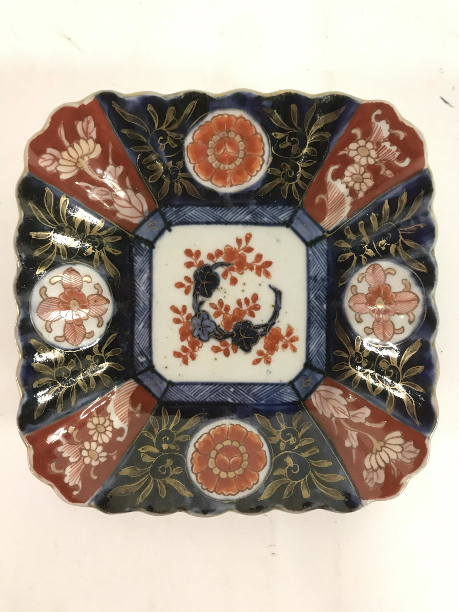 Antique Imari Porcelain Blue And Red Dish: Antique Imari Porcelain Blue And Red Dish, small black dots in white porcelain ceramic base, underside of dish has three blue rings painted and blue criss croos pattern around boarder, intricate hand 