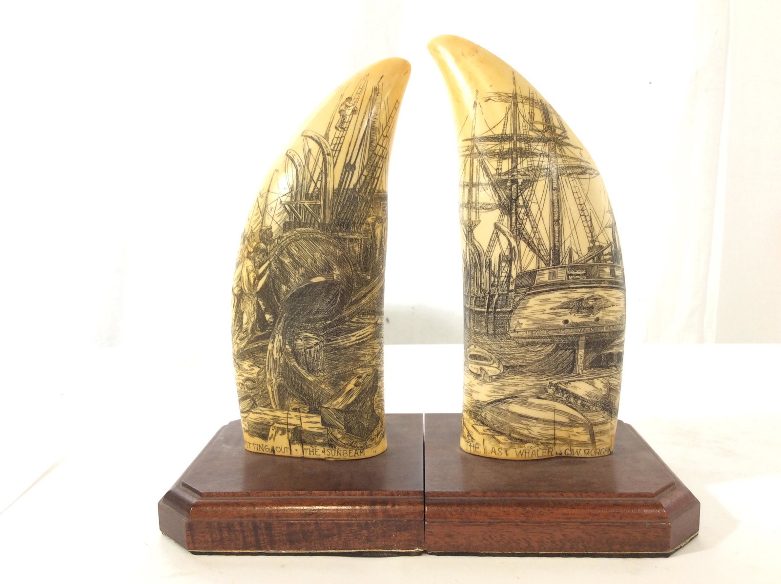 Pr Vintage Nwm Artek Replica Scrimshaw Bookends: Reads Nwm Artemis Replica On reverse, bookends with composite material in form of a scrimshaw/whales tooth, intricate etched details depicting nautical and maritime scenes, wooden pedestal bases, piec