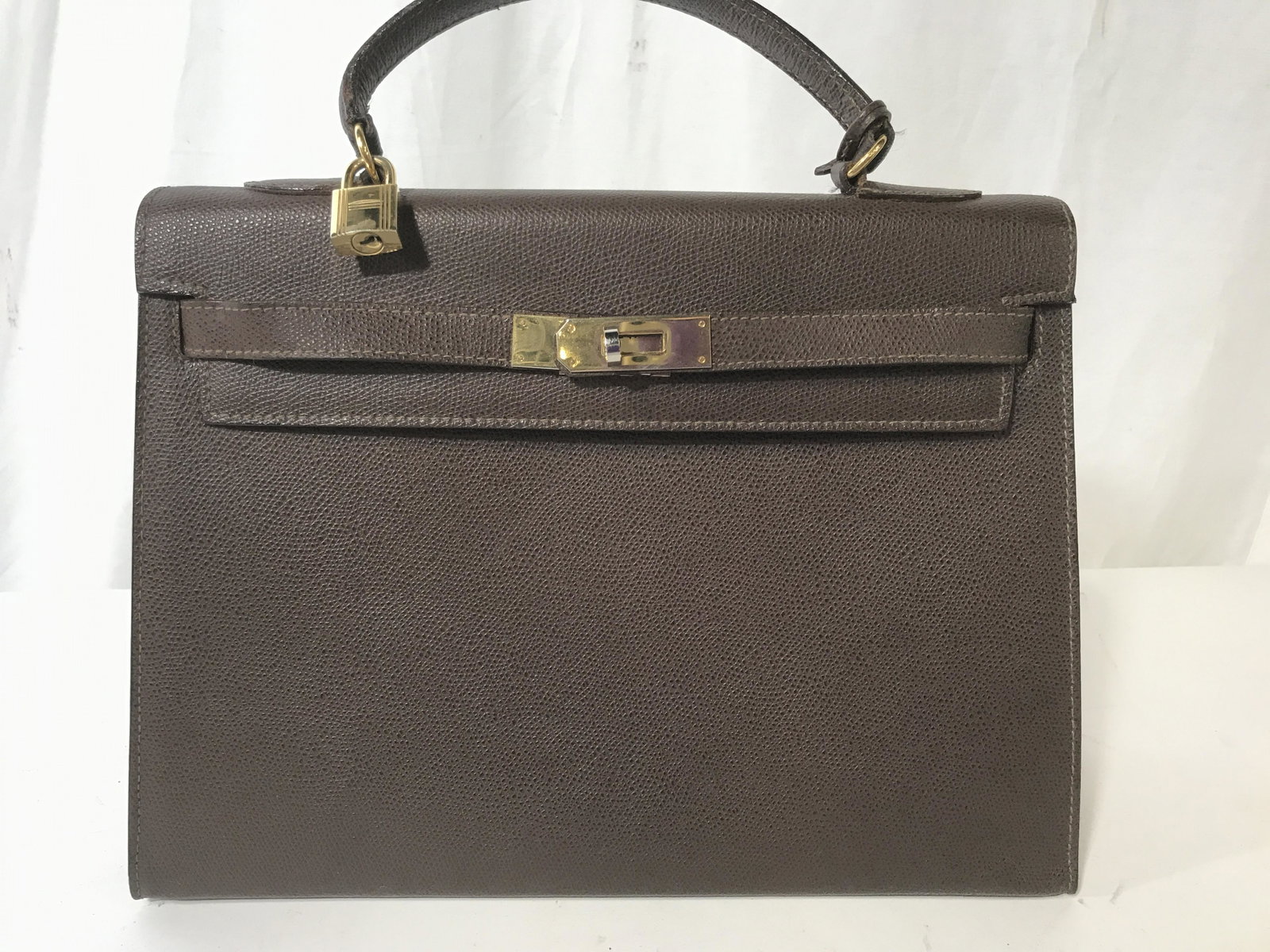 Designer REINA Pebbled Leather Handbag: Designer Handbag, Made In Italy, Brown pebbled leather,, twist lock closure with key & lock accessory, brass hardware & feet, measures 12x 9.5 in. 4.5 in. wide. Stamped REINA MADE IN ITALY. . Like new