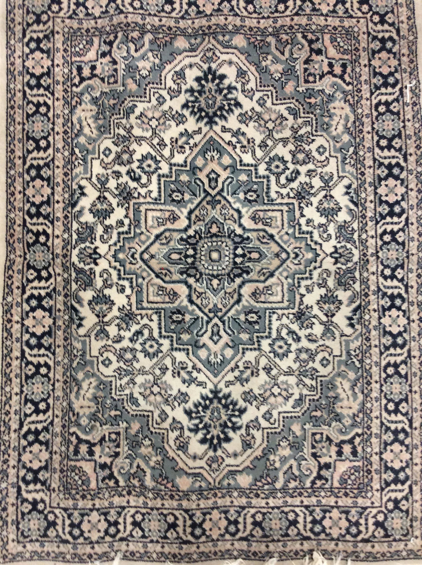 Vintage Oriental Design Throw Rug: Rug is wool & handmade. Label on underside reads DAKAR. Rug contains fringes, some of the fringes have worn. Contains multi toned floral leaf & vine detail. Contains tones of cream, beige, navy blue, 