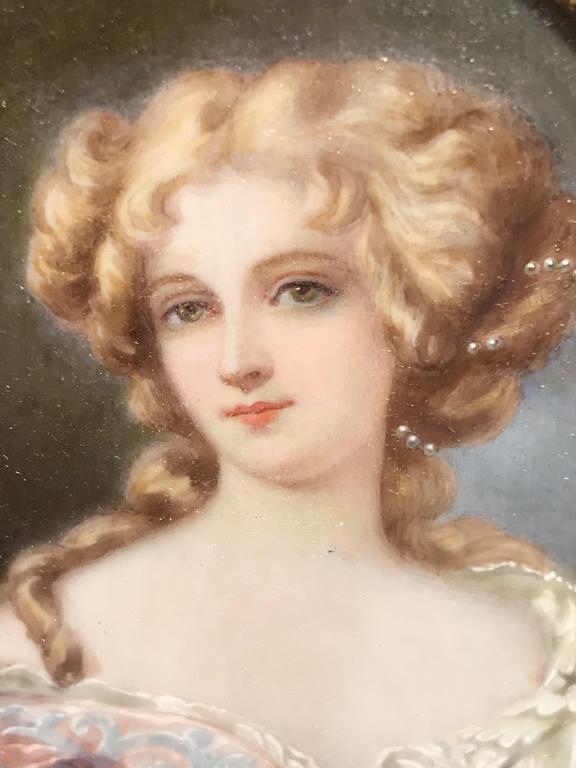 Antique Framed Hand Painted Portrait On Bone: This piece is an antique portrait painting of a woman, on bone. The piece is set beneath glass in a Pedestaled frame. The frame is crafted from leather and velvet, the frame is flanked by two hinged d