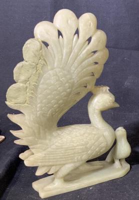 Pair Decorative Natural Stone Peacocks: Pair of green toned natural stone peacocks. Possibly jade or jadeite. Tails have been repaired with putty. Measures approx 9 inches tall and 6 inches wide. Pieces show a mother peacock with child. Pie