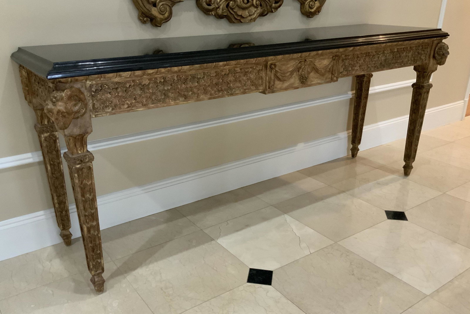 Antique Grand Gilded Carved Rams Head Console: Grand statement console table with custom black marble top, continental antique gold leafed hand carved wood table, Rams heads at front corners ornately carved apron and legs, neo classical style, gre