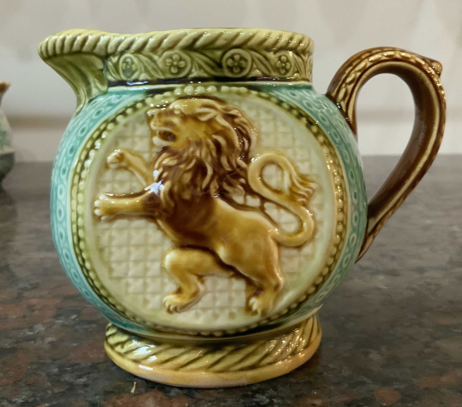Antique Majolica Lion Relief Pitcher, France: Antique Majolica pitcher vase vessel, brightly hued ceramic, pottery, collectible, standing lion relief round pitcher, measures ht 4.5 inches diameter 6.5 inches, marked underside illegibly, marked un