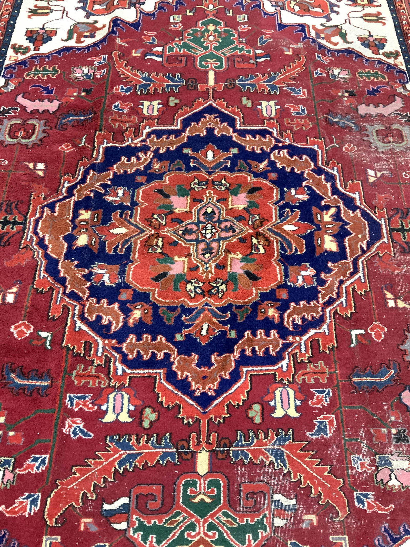 Handmade Antique Oversized Wool Rug: Rug is wool & handmade. Piece has fringes. Rug appears to be antique. Rug contains multi toned floral, leaf, & geometric detail including tones of crew, black, red, yellow, sea foam, blue, sand pink, 