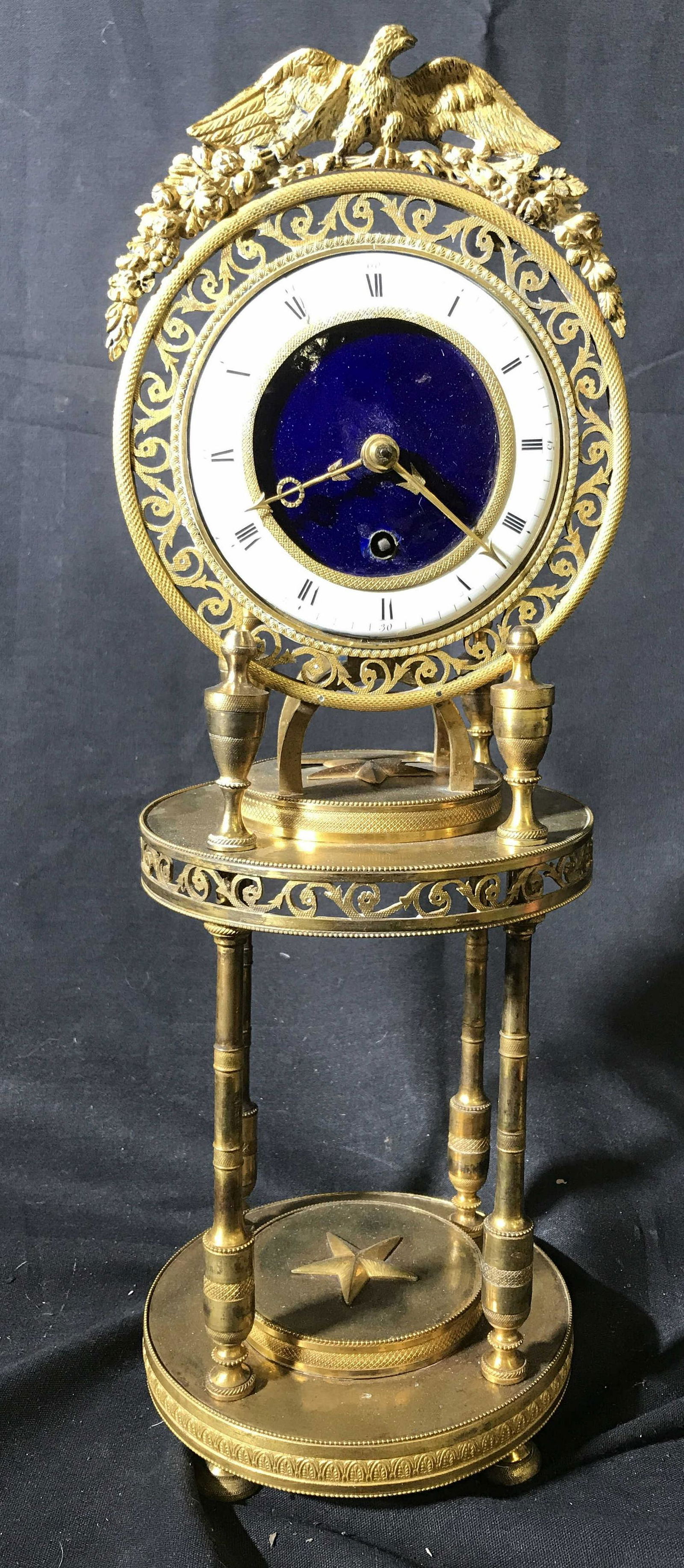 Vintage Star and Eagle Gilded Mantle Clock: Vintage possibly antique mantle clock with wreaths and Eagle as crown, and scratches form detailing, gold toned with blue white porcelain face, measures ht app 16 inches diameter app 6 inches, mantle