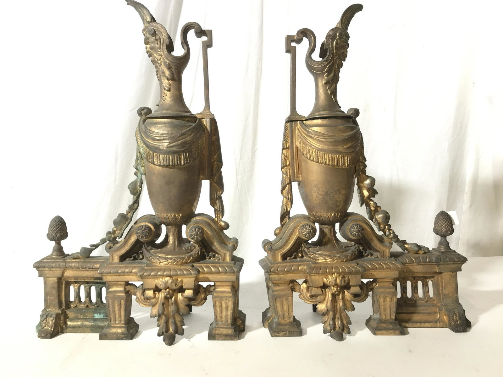 Pr Antique Gilded Metal Urn Form Andirons: Gilded metal antique andirons with gargoyle faces, scroll work, wreaths, columns, pillars, and pineapple finials, ornate and rich detailed hand wrought andirons, fireplace accessories, each measures h