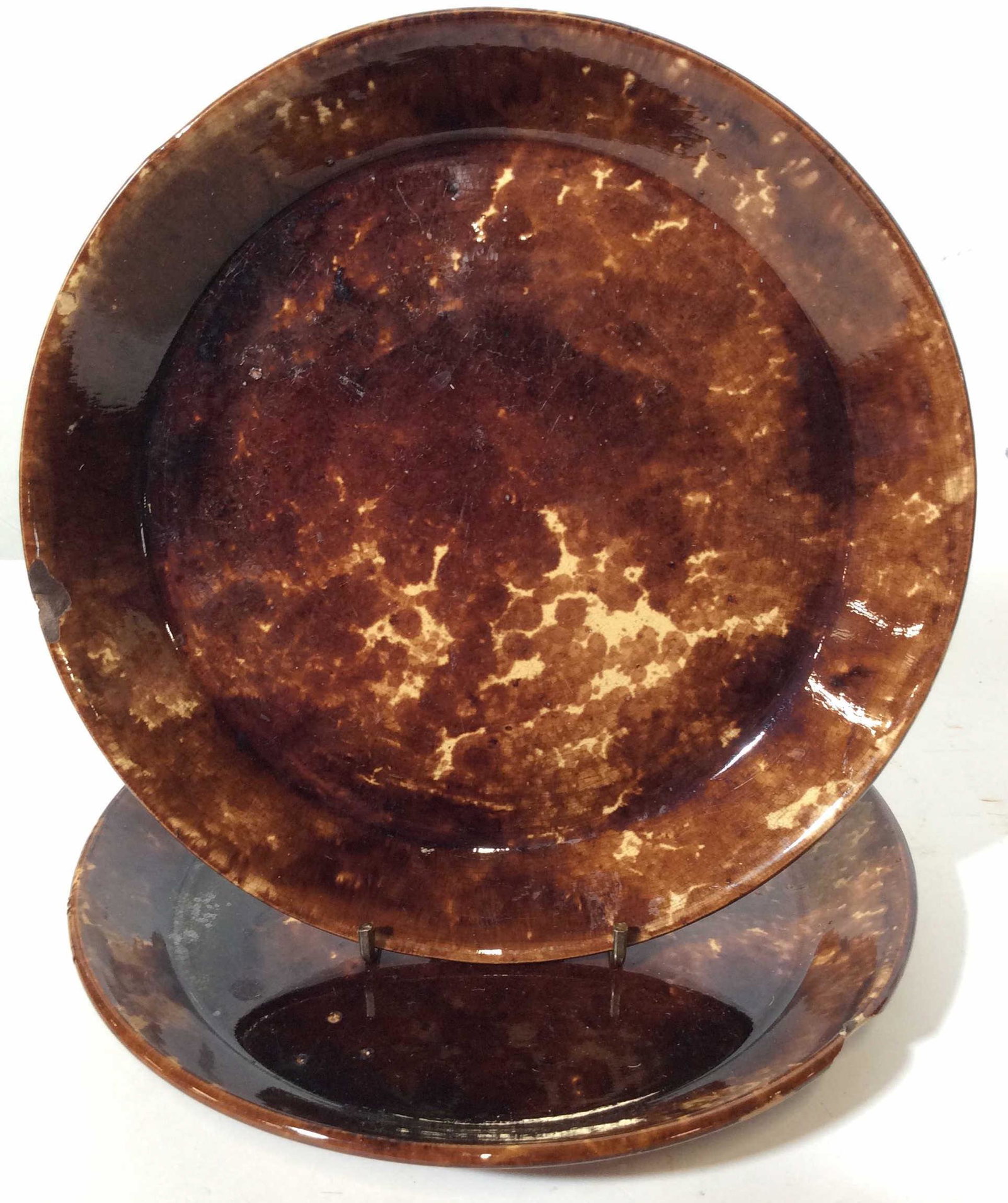 Pair Glazed Earthenware Dinner Plates: This lot includes two earthen ware dinner plates. The plates are glazed, and colored in chocolate tones. There is some chipping present, as well as crazing. The plates measure approx 10 inches in diam