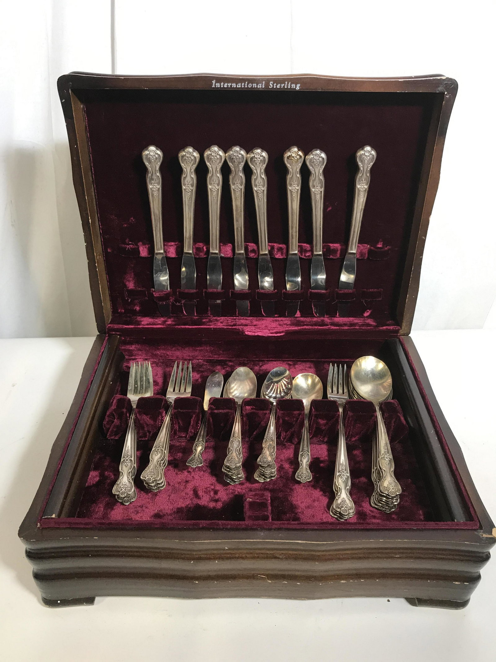Lot 43 WM ROGERS Silver-plated Dining Utensils: This lot includes 43 vintage dining utensils, including knives, forks, and spoons. The utensils are contained in a velvet lined wooden box. The underside of each utensils reads WM ROGERS MFG CO, EXTRA
