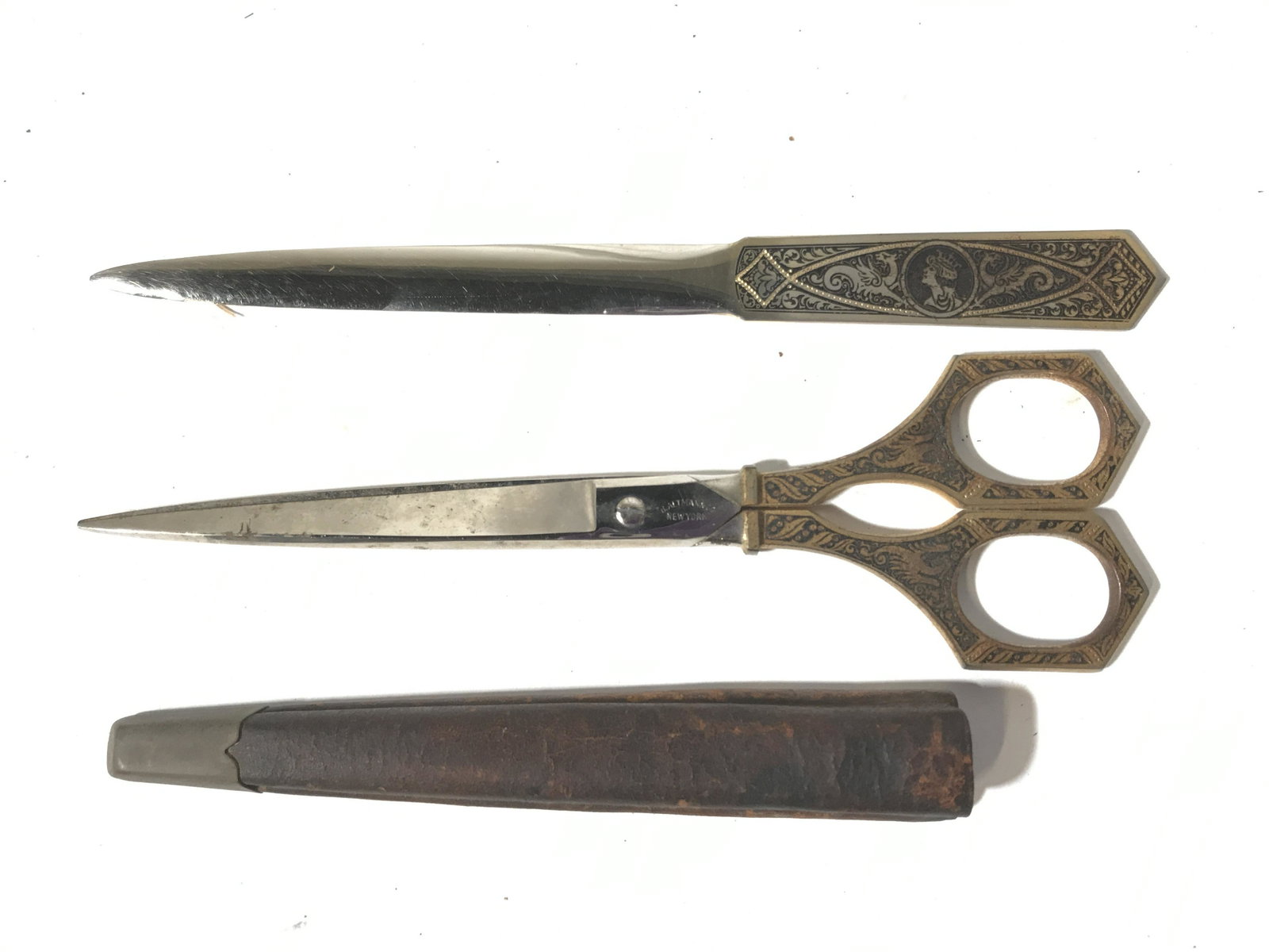 Vintage Scissors & Letter Opener, Germany: This lot includes a vintage pair of scissors as well as a letter opener. The handles of both the scissors and the letter opener are intricately detailed and gold toned. The largest piece measures appr