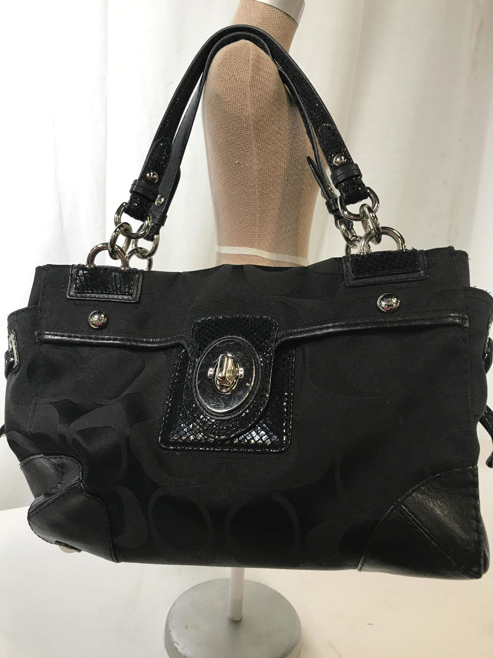 Black COACH Handbag, no. J0969-14507: Authentic Coach ladies Bag, pre owned, silver toned hardware, 3 interior large compartments, blue lining has some discoloration from use. Section of wear on handle. 13 x 8 x 5 in. Underside metal feel