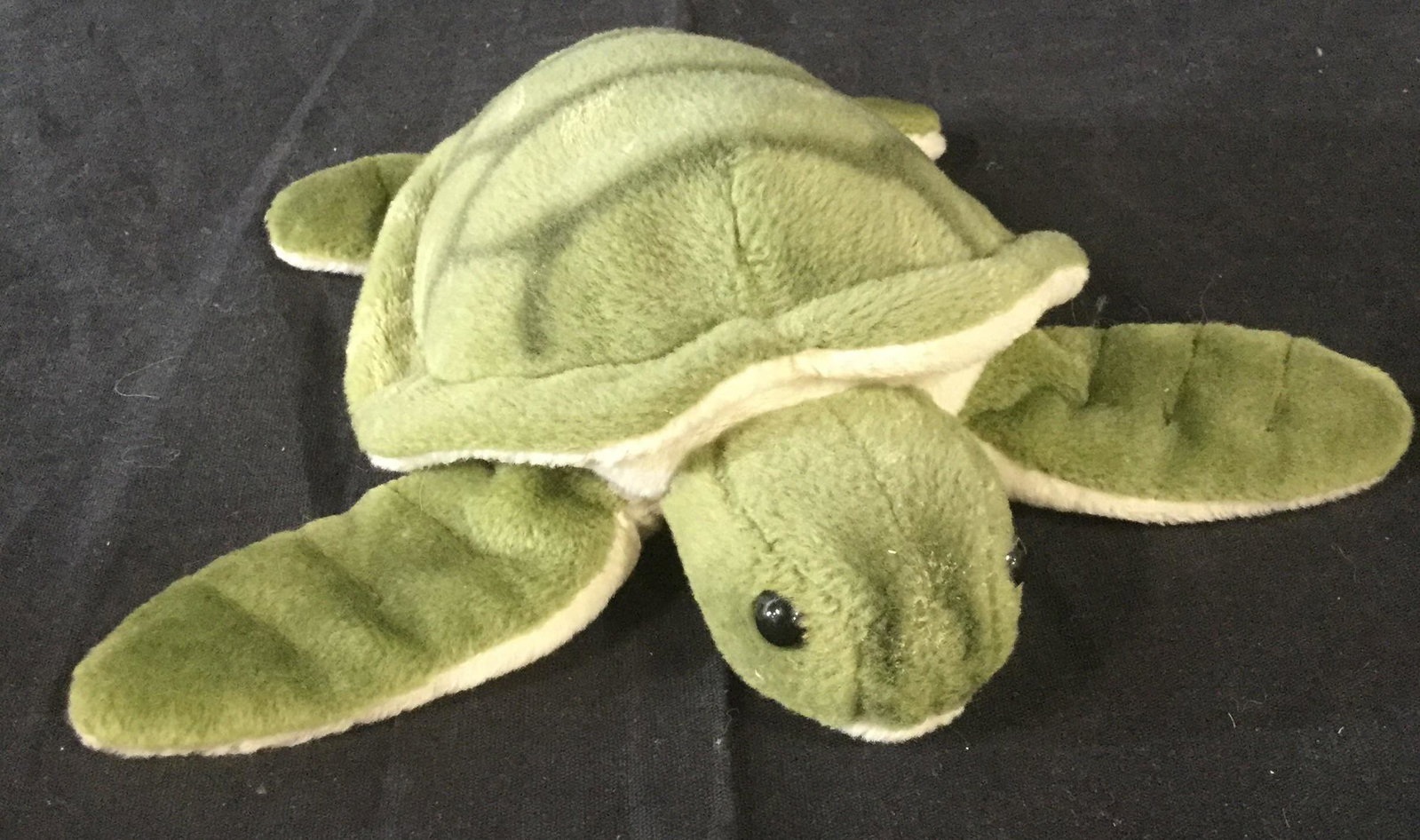 Stuffed PLUSH turtle: Plush stuffed toy of turtle. Details include sewn darts on arms and legs. Detailed back with turtleshell design. Cream underbelly also with colored and sewn detailing. Lays on belly and has black bead