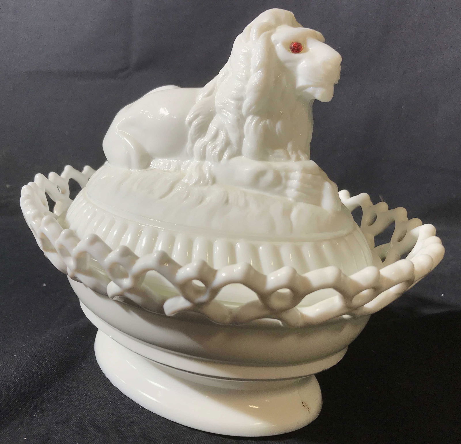 Vintage Milk Glass Lion Form Lidded Vessel: Vintage possibly antique milk glass lion with red eyes, Library lion style sits in frettework pedestal bowl, lidded vessel, collectible table ware, measures ht 8 inches length app 9 inches,underside o
