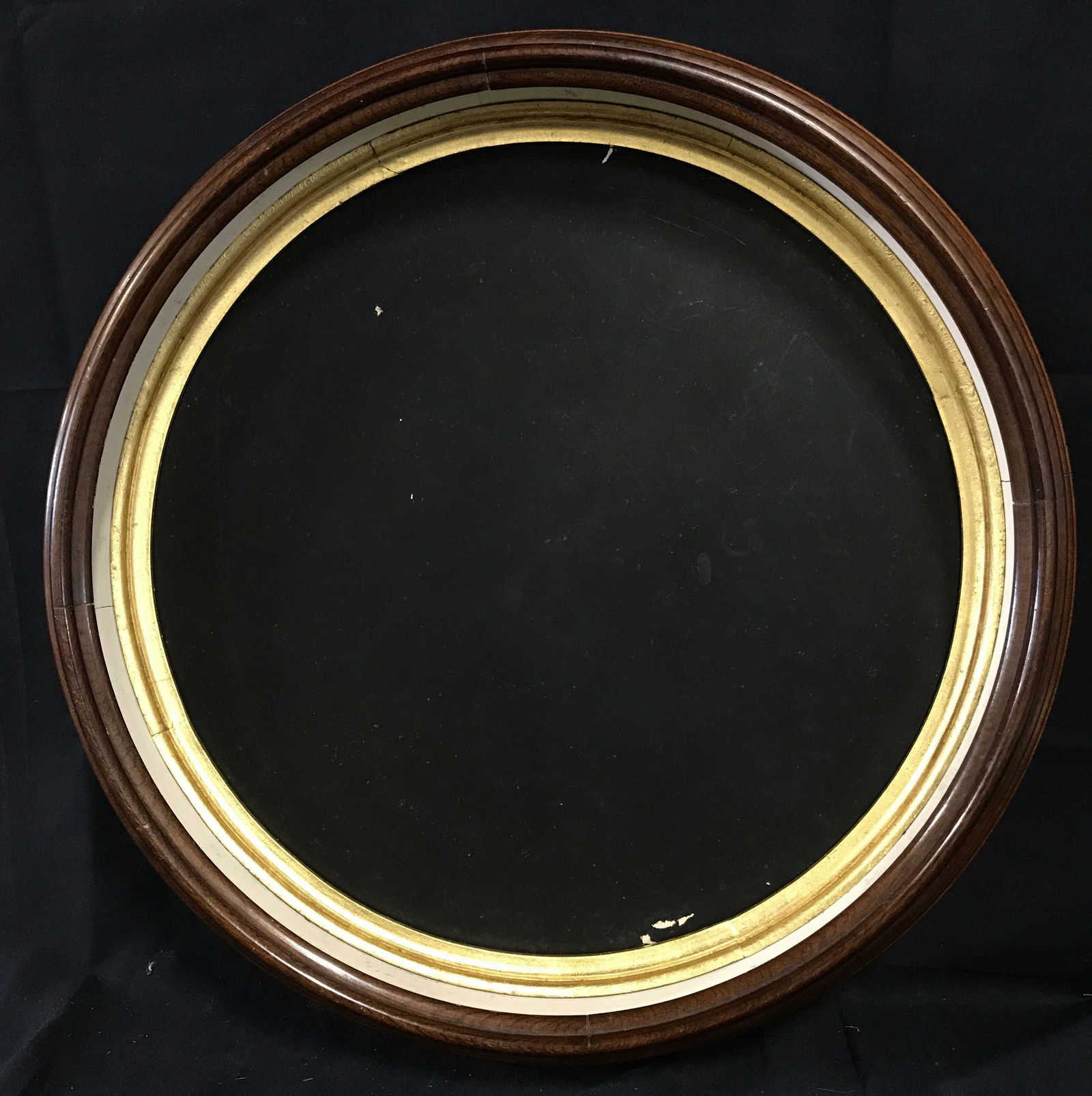 Round Shadow Box Frame: Round shadow box frame, dark wood frame painted white interior, gilt wood inner frame, black board backing stapled into frame with industrial staples, one staple is missing on the back, no glass to fr