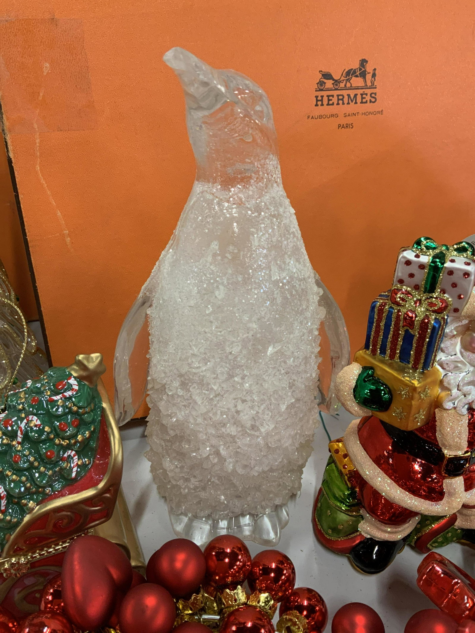 Hermès Box Lot Christmas Decor: As found, Hermès Box measuring 14 inches square 6 inches deep with Christmas holiday decorations including two Christmas wreaths with red glass balls, ceramic sleigh box that opens with spinning scen
