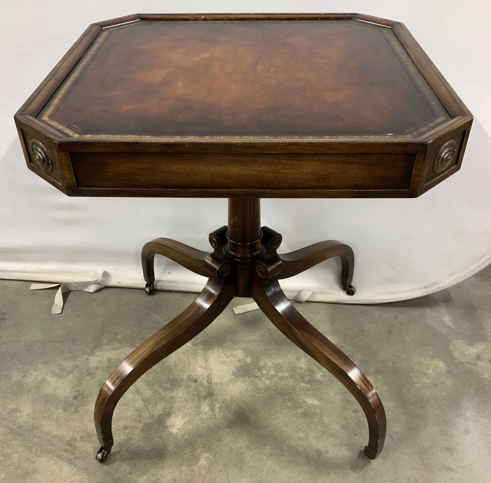 Pair WEIMAN Tooled Leather Wood End Tables: Marked underside for WEIMAN, each table has gold embossed tooled leather tops, wood frame center pedestals and four scrolled legs on casters, measure ht 28 inches tops measure 24 inches square, vintag
