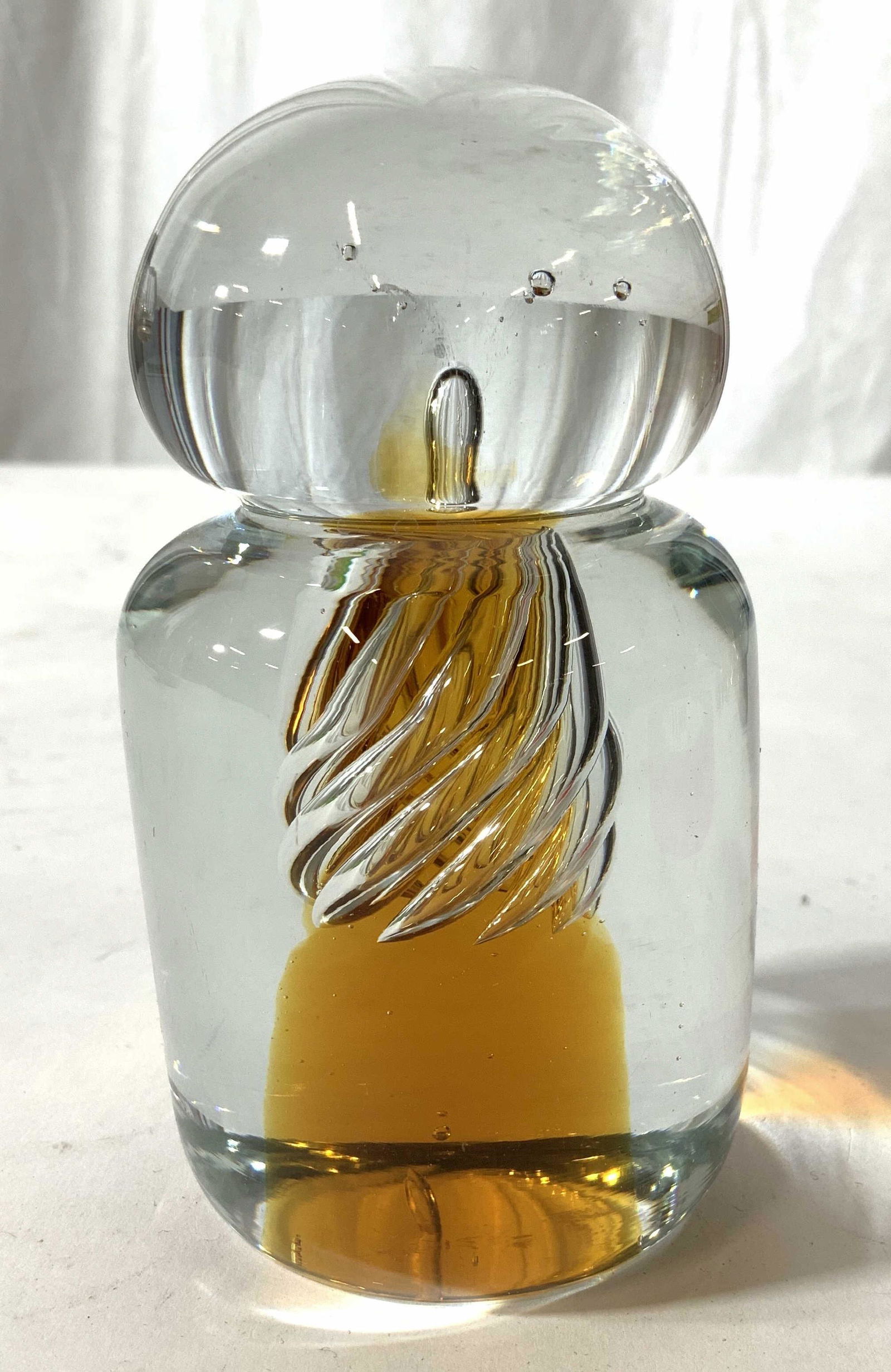 Mid Century Art Glass Amber and Clear Paperweight: No apparent Signature, possibly Blenko or Murano Art Glass. Hand crafted hand formed art glass paperweight, sculptural, modern figural, clear and amber toned cylindrical, base with orb top, inside swi