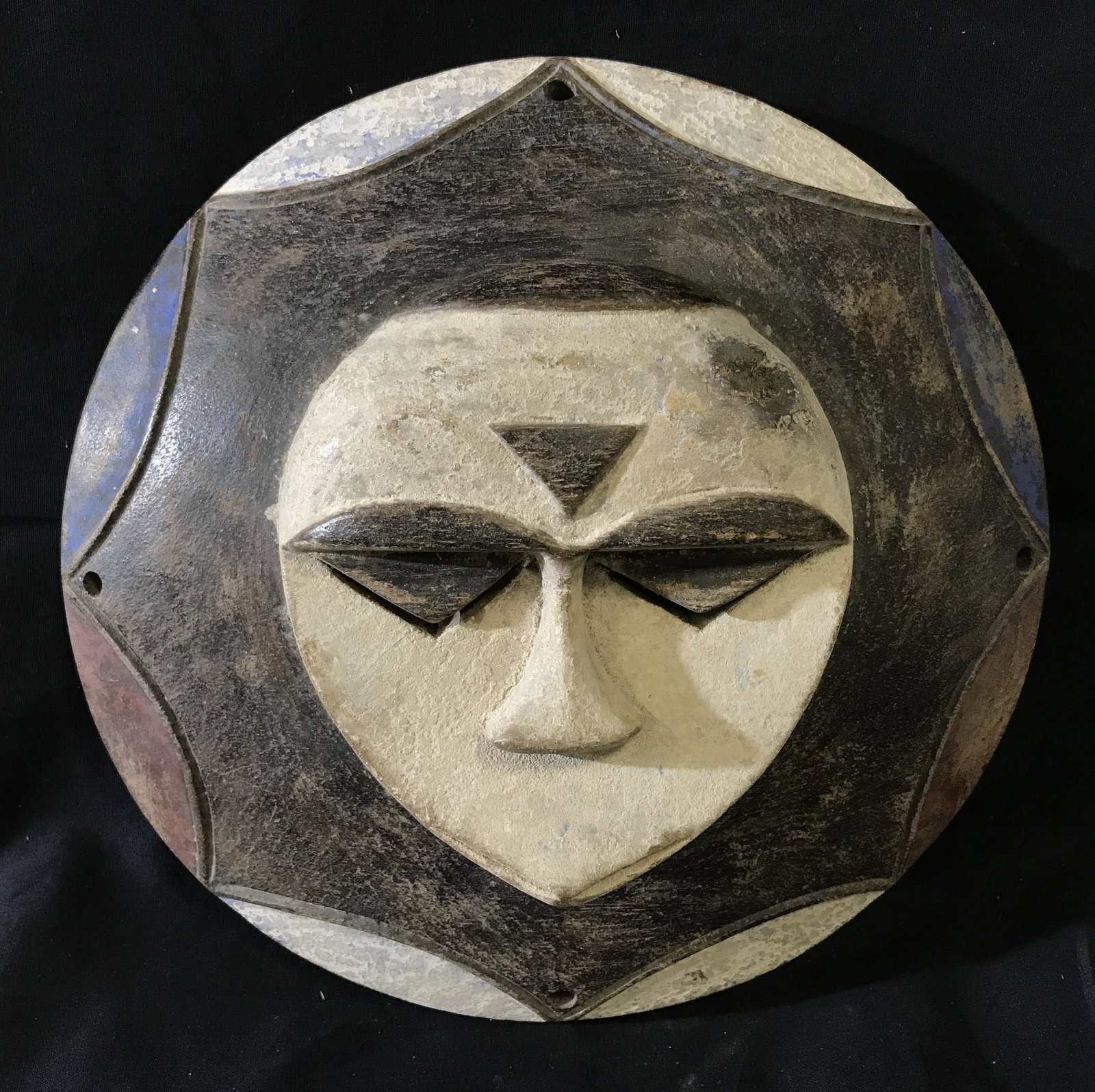 Nigerian Eket Mask: Nigerian Eket Mask, sun mask, origins found in Nigeria West Africa, holes made on four sides, painted with white black brown and blue paint, hand carved from one piece of wood, measures 12 inches in d