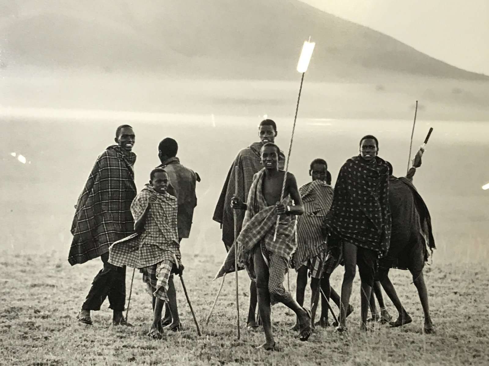 Photograph of Boys on Landscape: Photograph, subject young men and boys on African Landscape with spears, picture taken in greyscale, black border added, white matting, silver and black painted frame, chips and wear to frame, label t
