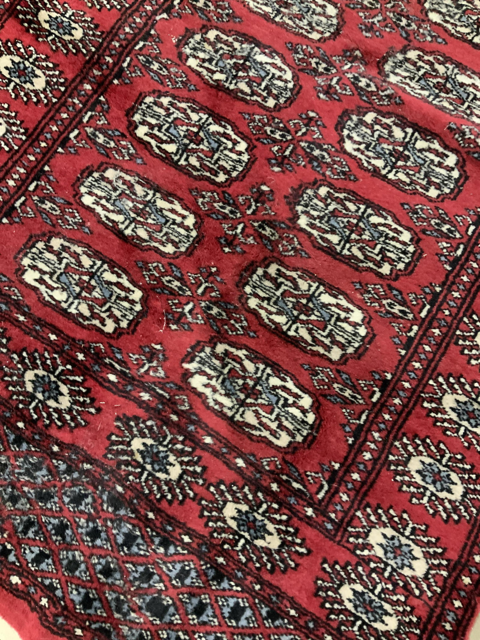 Hand Made Oriental Wool Carpet: Deep maroon toned with blue black white accents, fringe at two ends, area rug, carpet, oriental carpet, home furnishings, home decor, vintage carpet has wear consistent with age and use, property of G