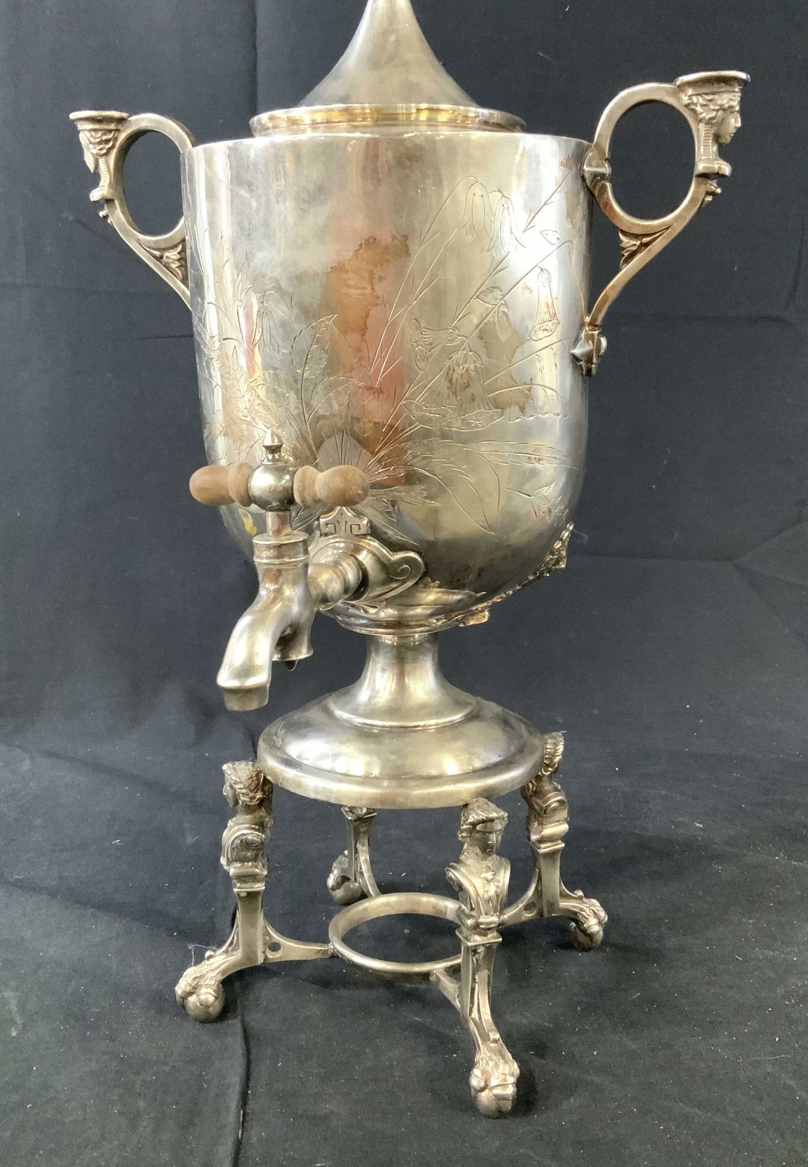 Silver Toned Etched Samovar: Drinks dispenser, samovar, urn, table ware, has four ball and paw feet, Egyptian style busts in relief, and lion head accents, measures ht app 20 inches, diameter to handles app 11.5 inches