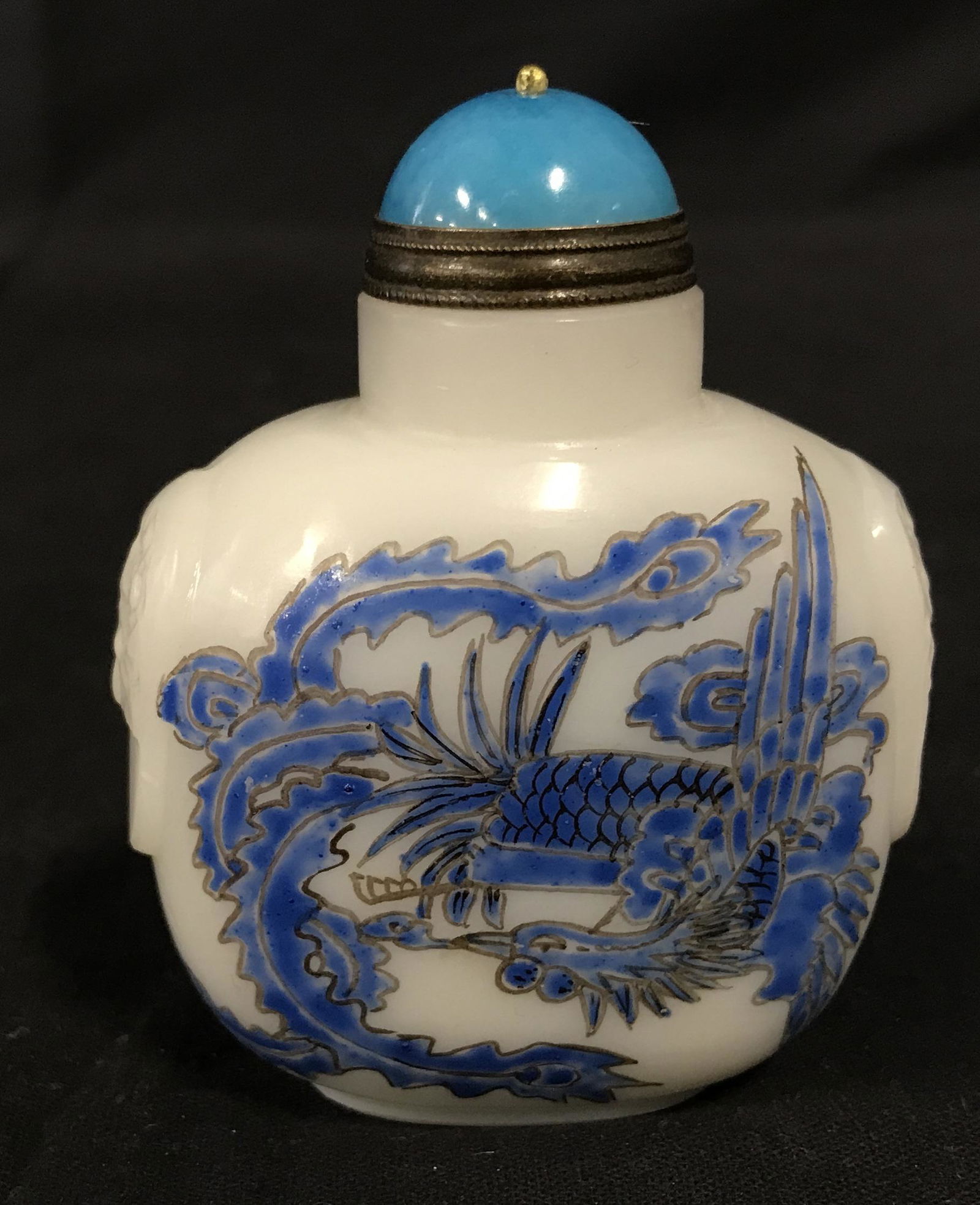 Hand Crafted Porcelain Asian Snuff Bottle: Hand crafted Porcelain Asian snuff bottle, text on bottom in red possibly Chinese, carving on bottles depicts a dragon in blue on white white text imprinted on the sides, metal inlay on top of bottle,