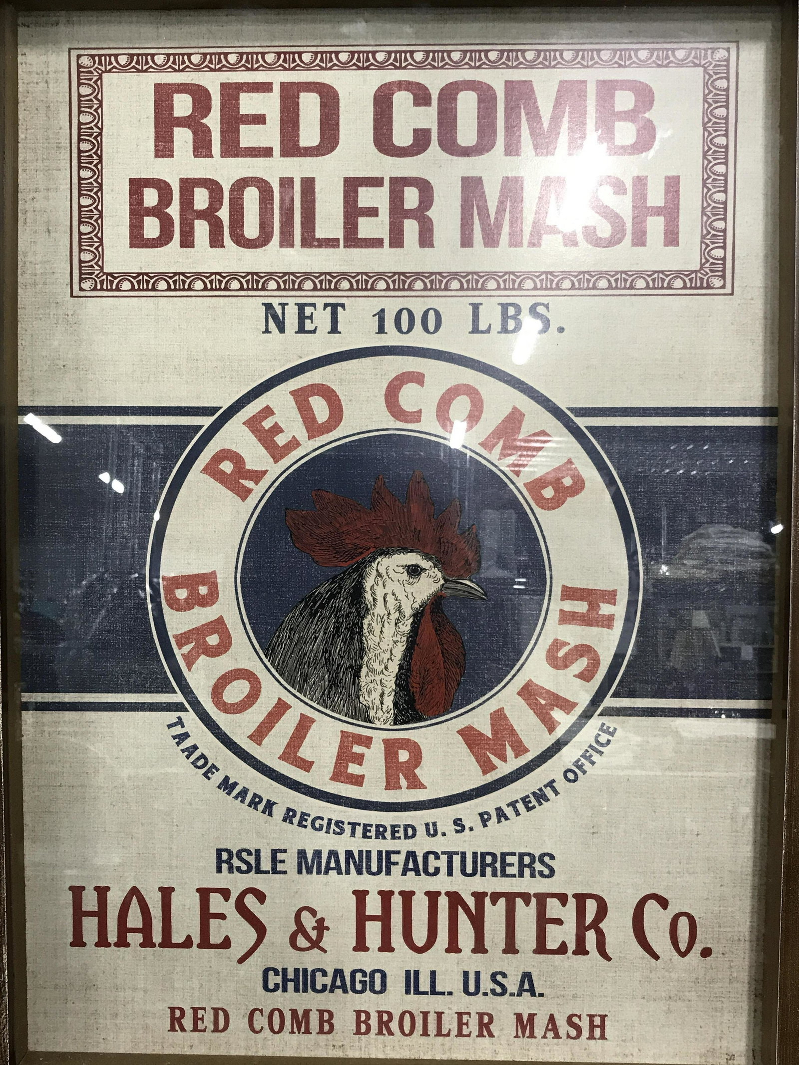 Framed Advertisement Red Comb Broiler Mash: Framed Advertisement, ad displays text and the head of a chicken on a white and blue background, text on ad from top to bottom reads ‘Red Comb Broiler Mash, Net 100 LBS., Red Comb Broiler Mash, Trad