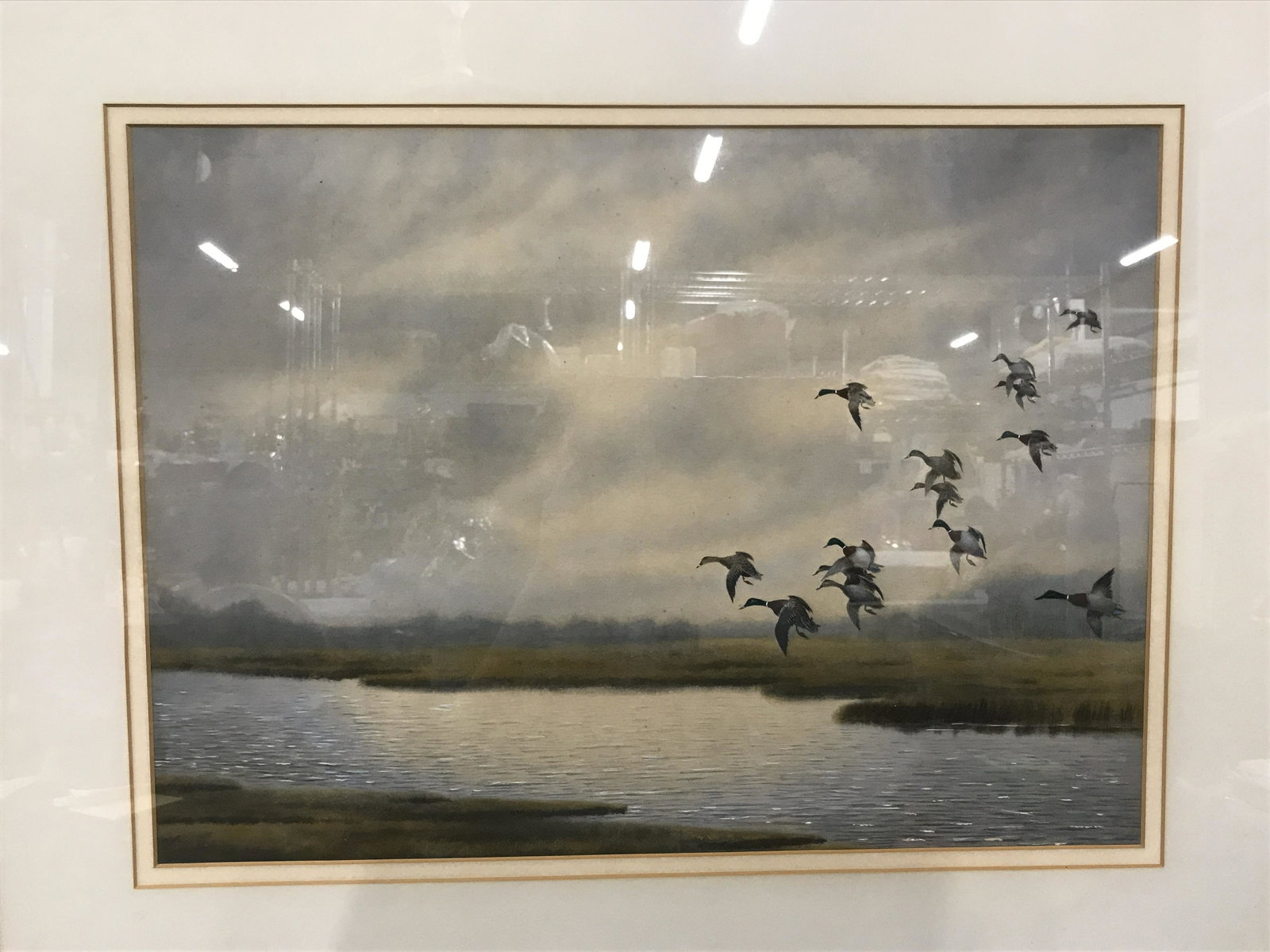 Offset Lithograph Nature Scene: Offset Lithograph nature scene, no apparent signature, subject ducks in flight over a river running through marsh lands during sunrise, double matting in white and tan, wooden frame with gilded trimmi