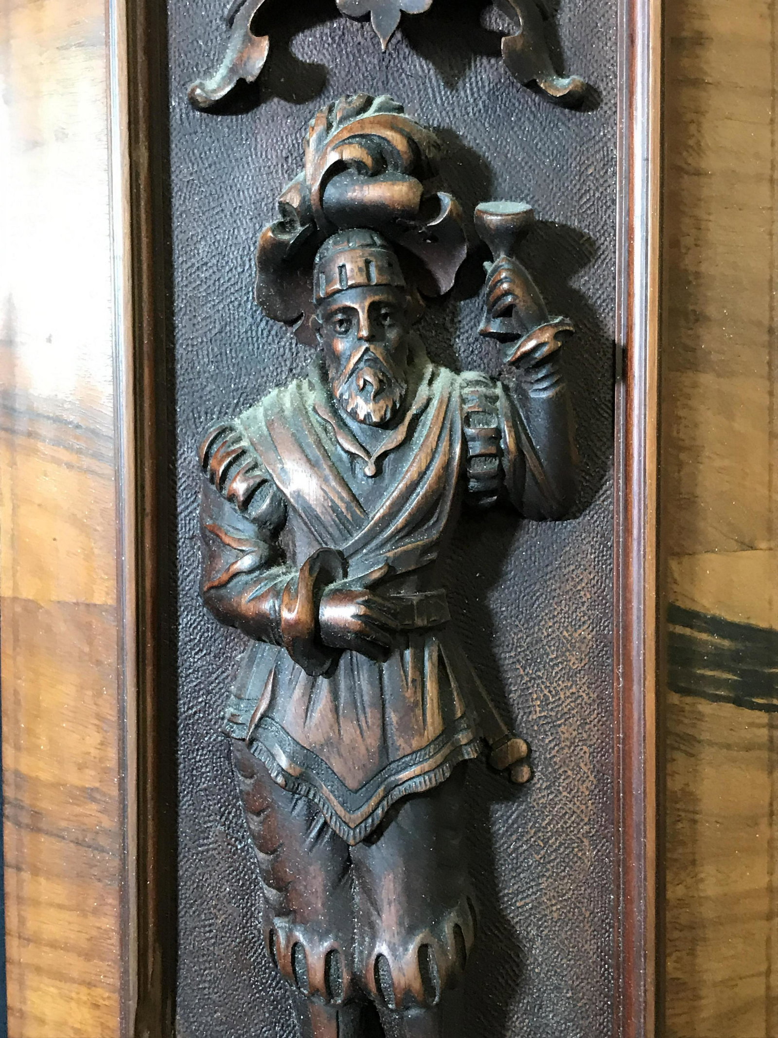 Pair Medieval Style Wood Carving Plaques: Pair medieval style wood carvings, no apparent signature, subject each depicts a man in medieval style clothing with a glass raises in hand standing atop a shelf with an egg like dome above them, some